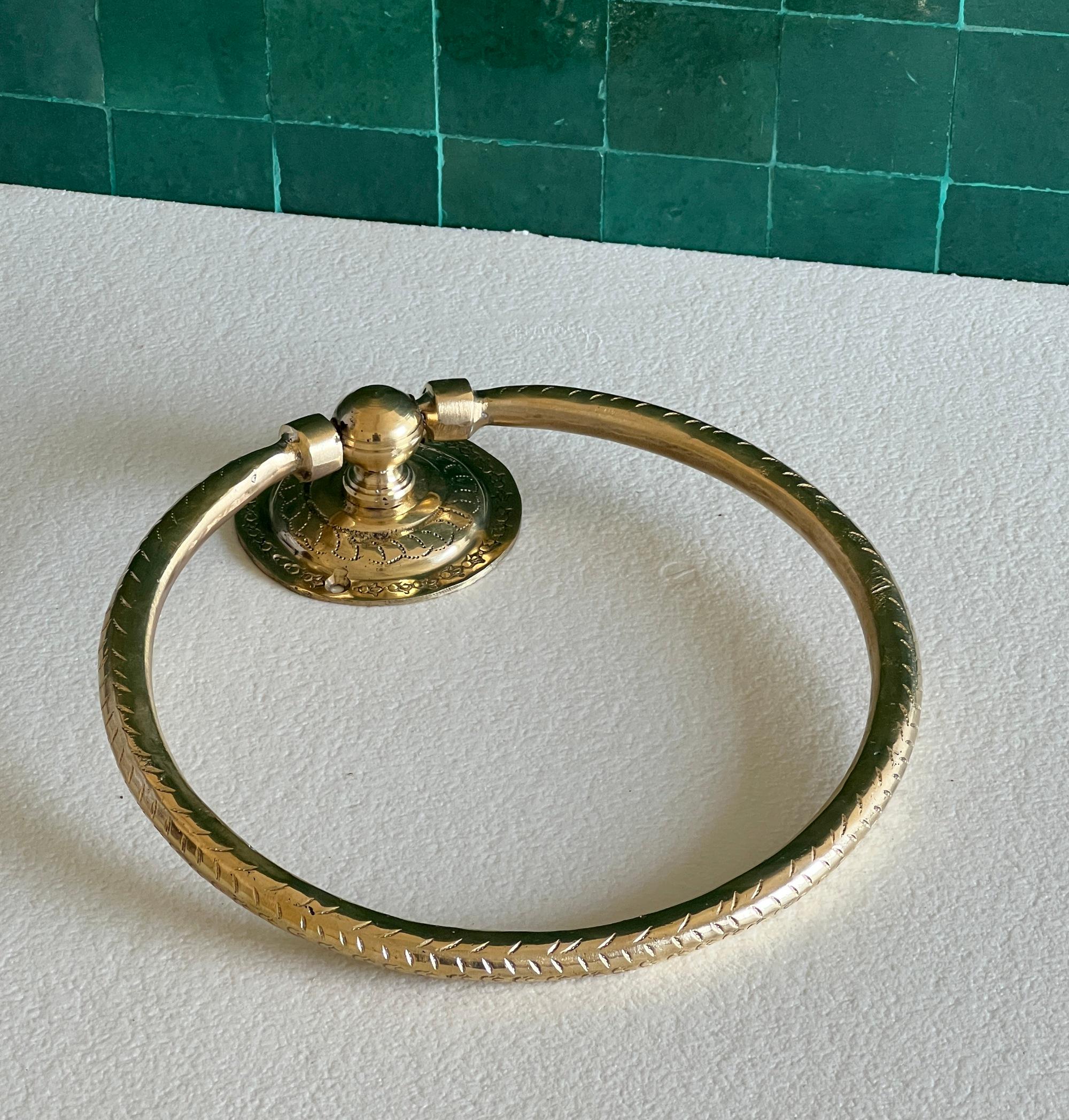 Handcrafted brass wall hook mounted in a bathroom holding a towel 