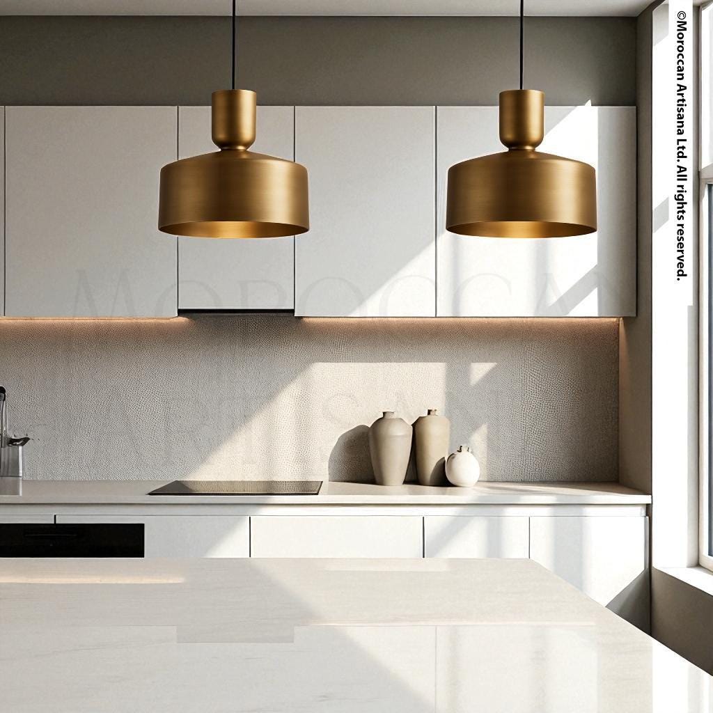 a modern kitchen with white cabinets, a sleek countertop, and two gold pendant lights hanging above the counter.