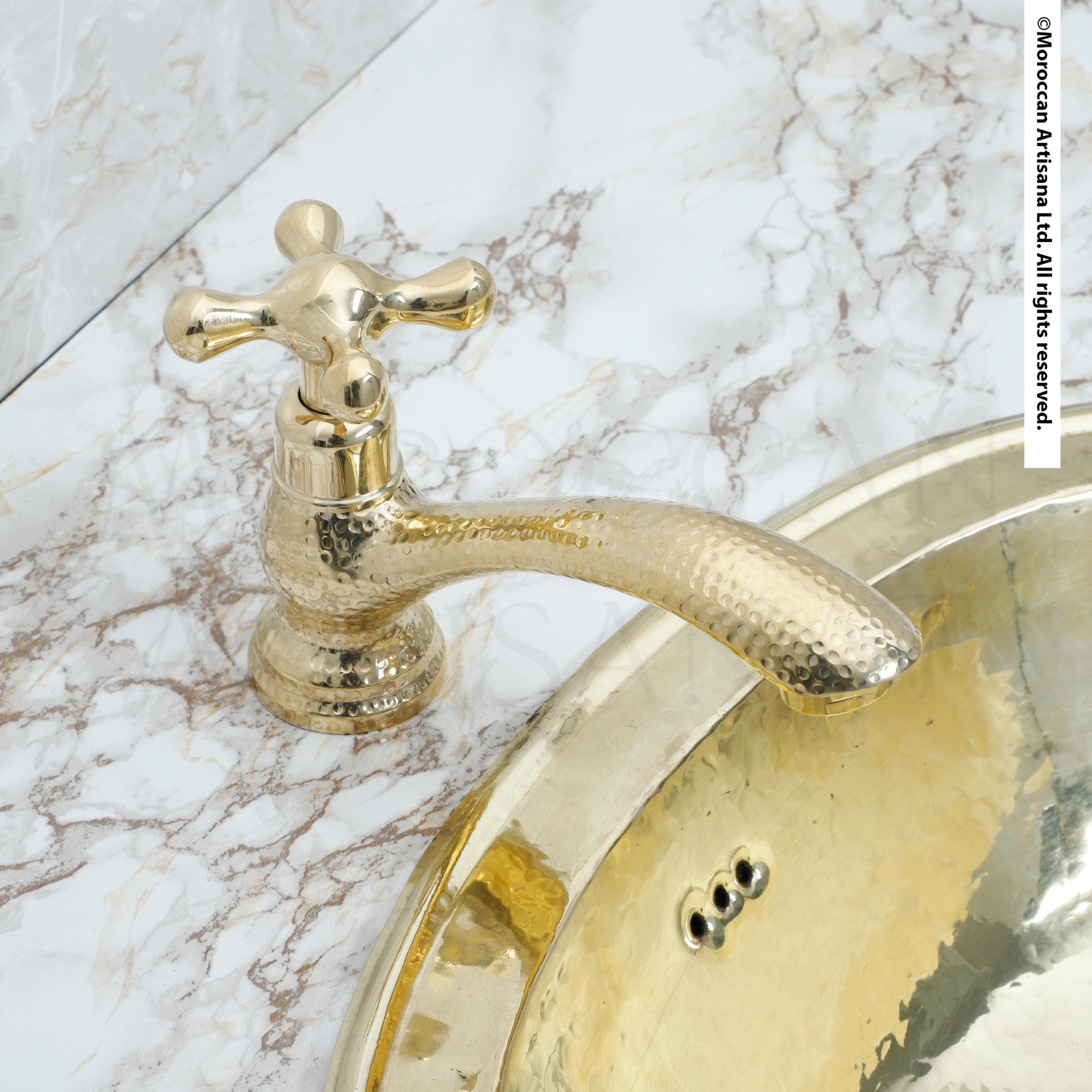 a gold-colored faucet and a marble-like countertop.