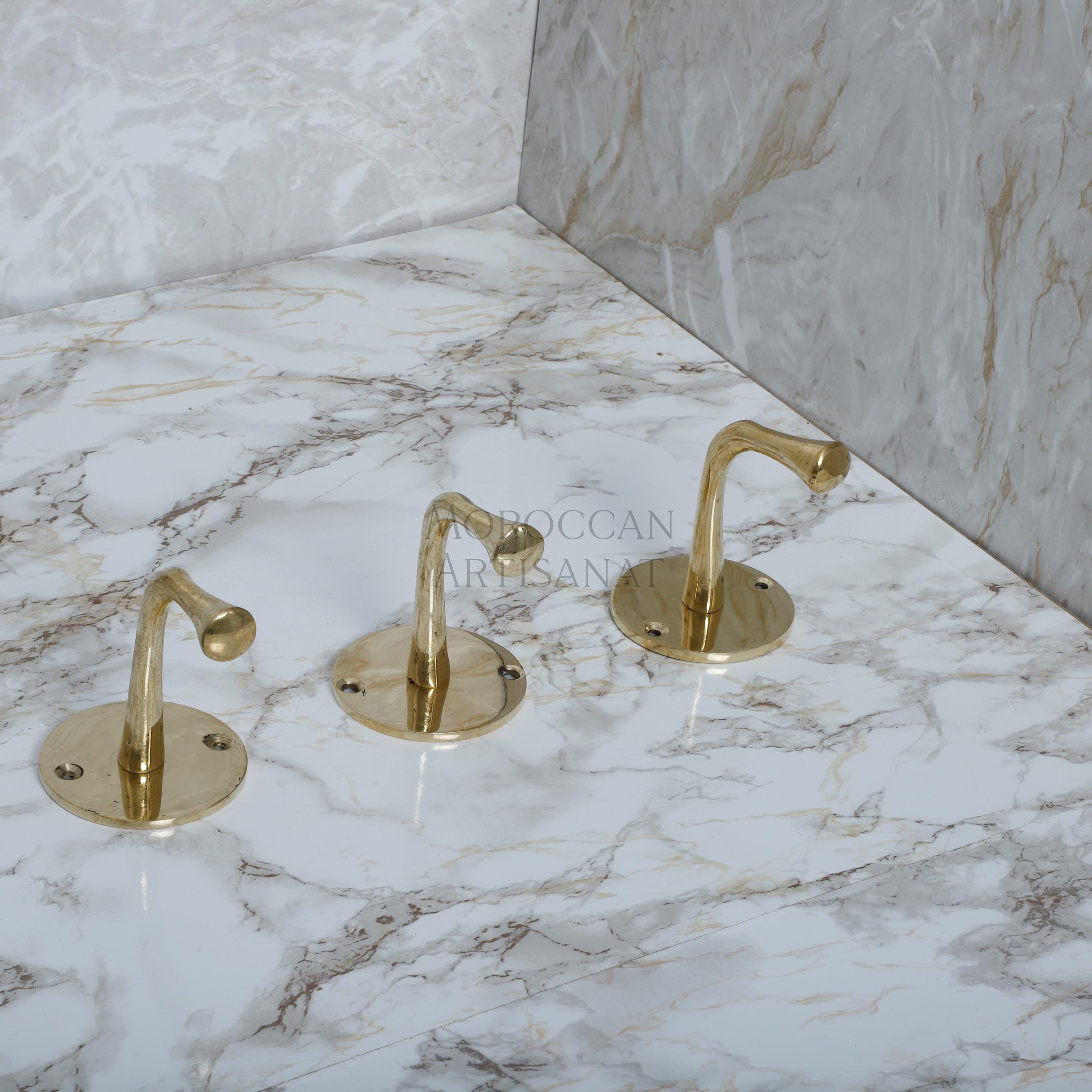 a marble counter top with three golden faucets