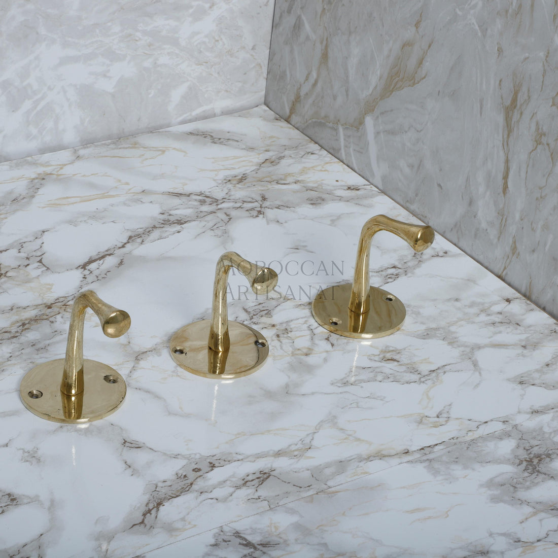 a marble counter top with three golden faucets