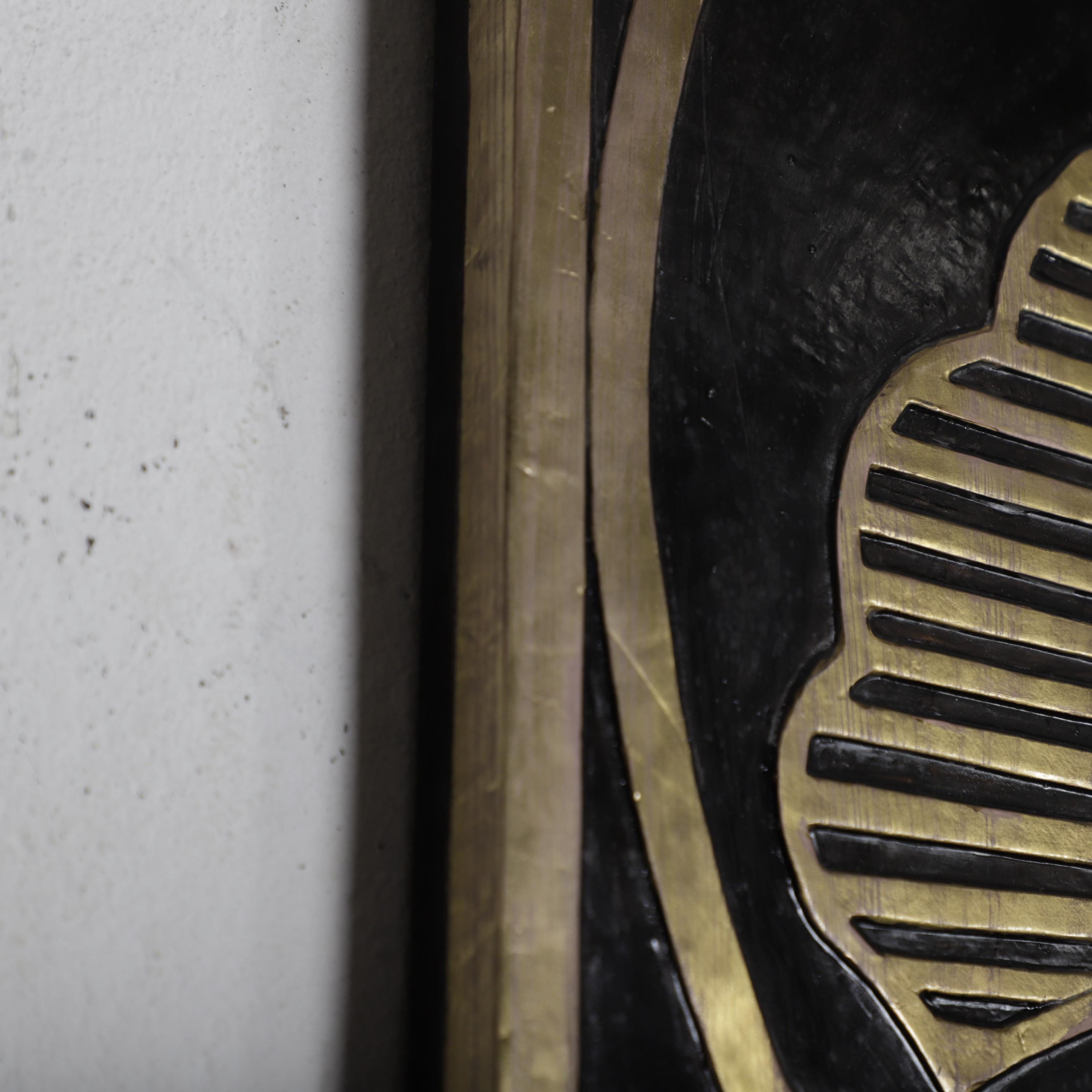 a close-up view of a black and gold decorative element, possibly a piece of wall art or a sculpture, with a textured surface and a gold border.