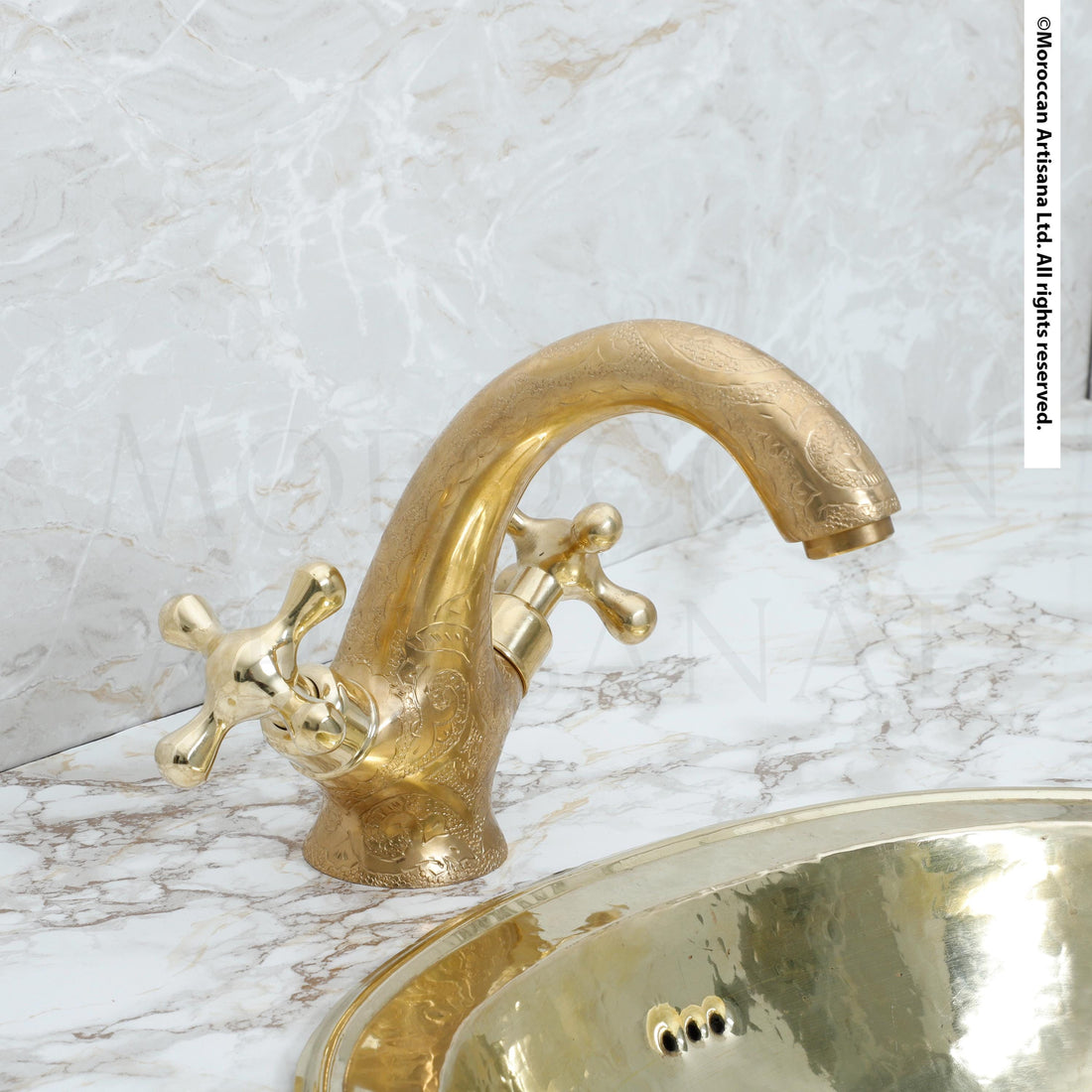 a gold-colored bathroom sink with a decorative faucet, set against a marble countertop.