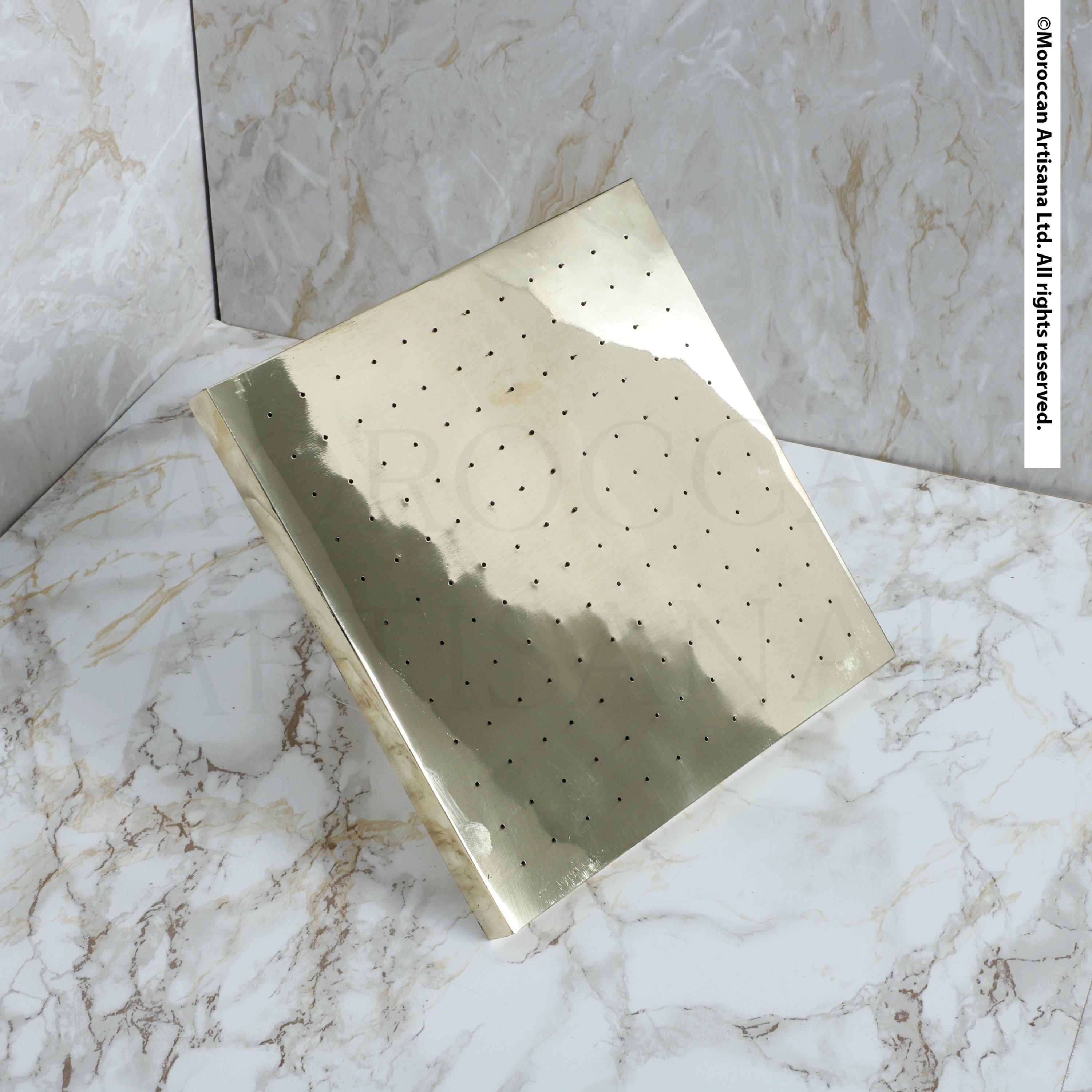 a square-shaped metallic object with a grid-like pattern on its surface, placed on a marble surface.