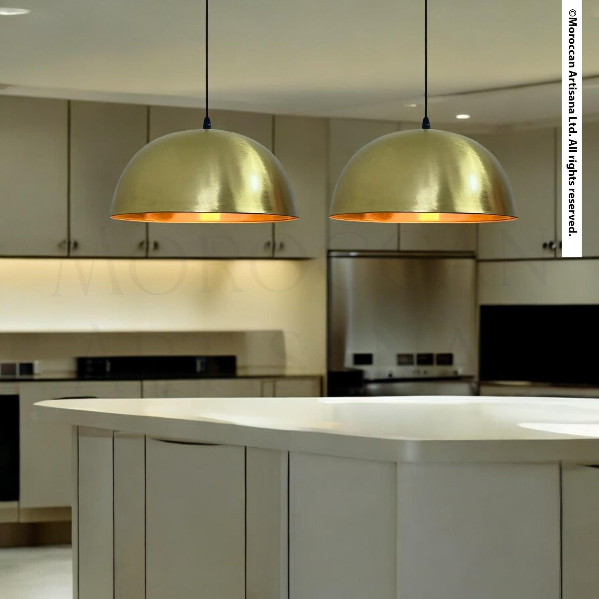 a modern kitchen with a large, white island and two gold pendant lights hanging above it.