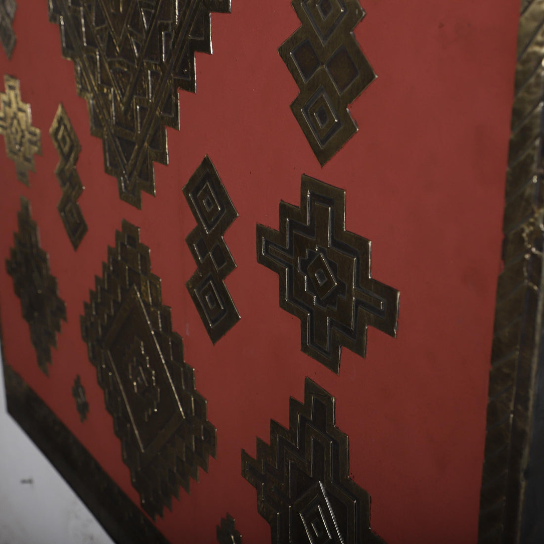 a close-up view of a red surface adorned with intricate geometric patterns and designs, including various shapes and symbols.