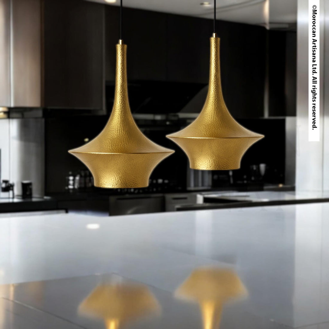 two gold pendant lights hanging from the ceiling in a modern kitchen.