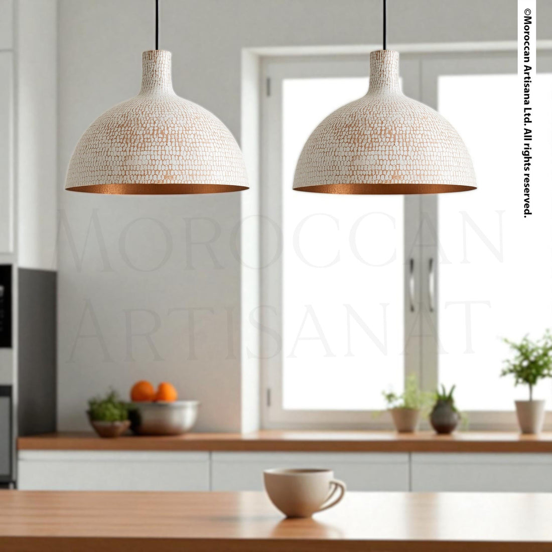 a modern kitchen with two pendant lights hanging above a wooden table. The table is set with a coffee cup and a bowl of fruit, creating a cozy and inviting atmosphere.