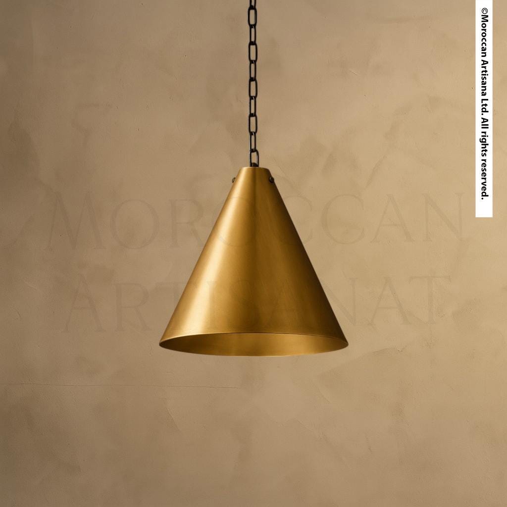 A single, gold-colored pendant light hangs from a chain against a beige background.