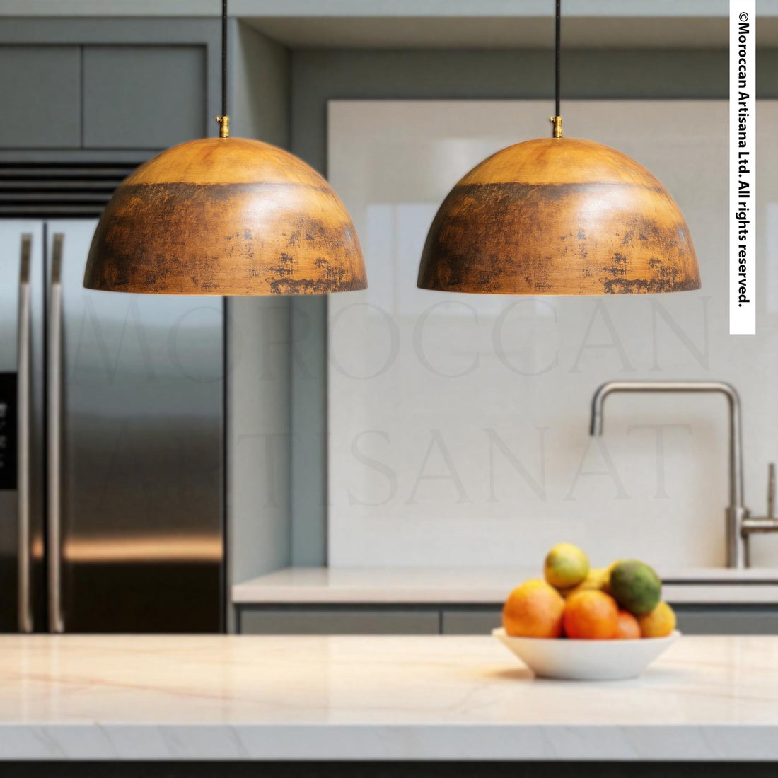 a kitchen with two hanging pendant lights, a bowl of fruit on the counter, and a stainless steel refrigerator in the background.