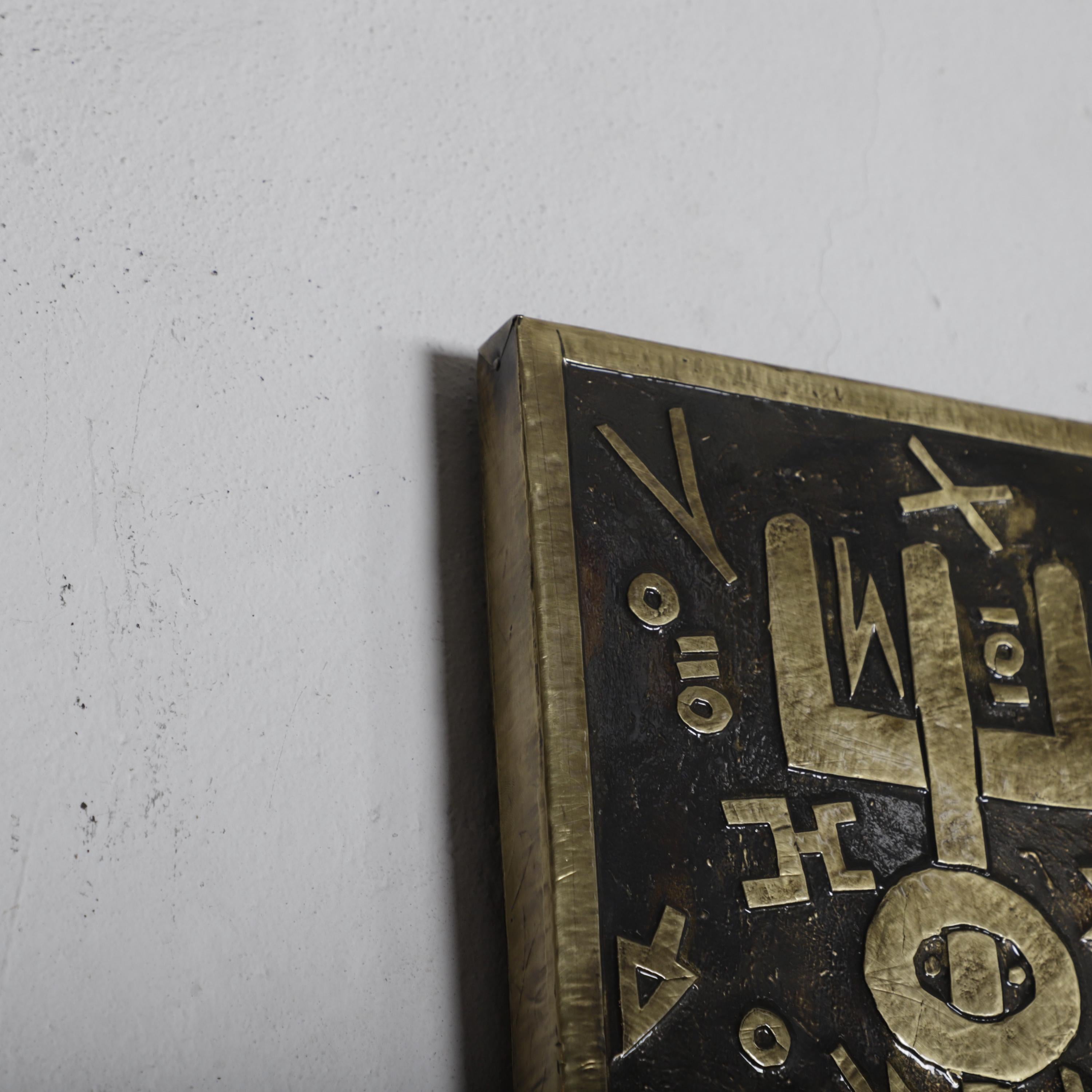 a close-up view of a dark, ornate metal plaque or artwork with intricate designs and patterns.