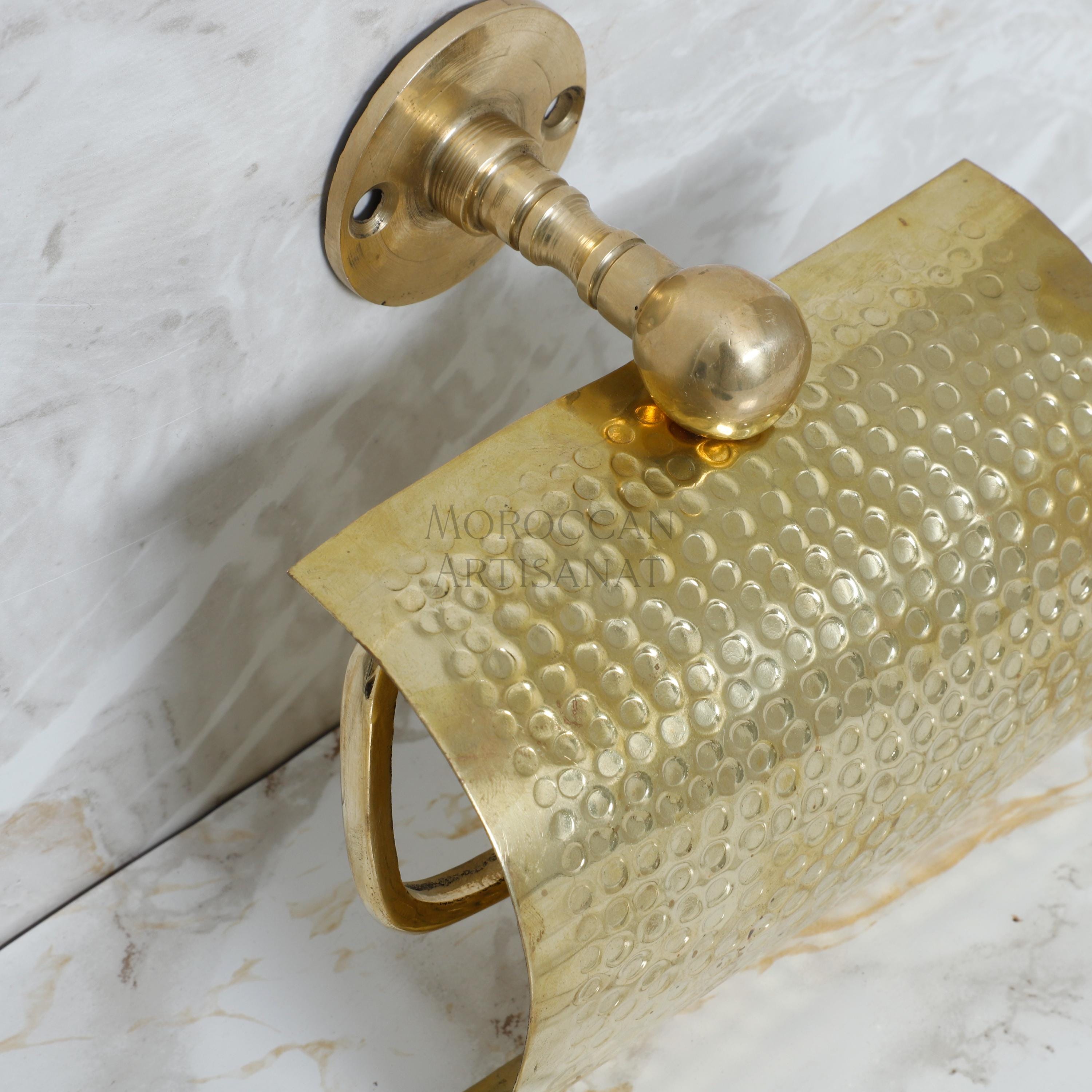a gold toilet paper holder on a marble counter