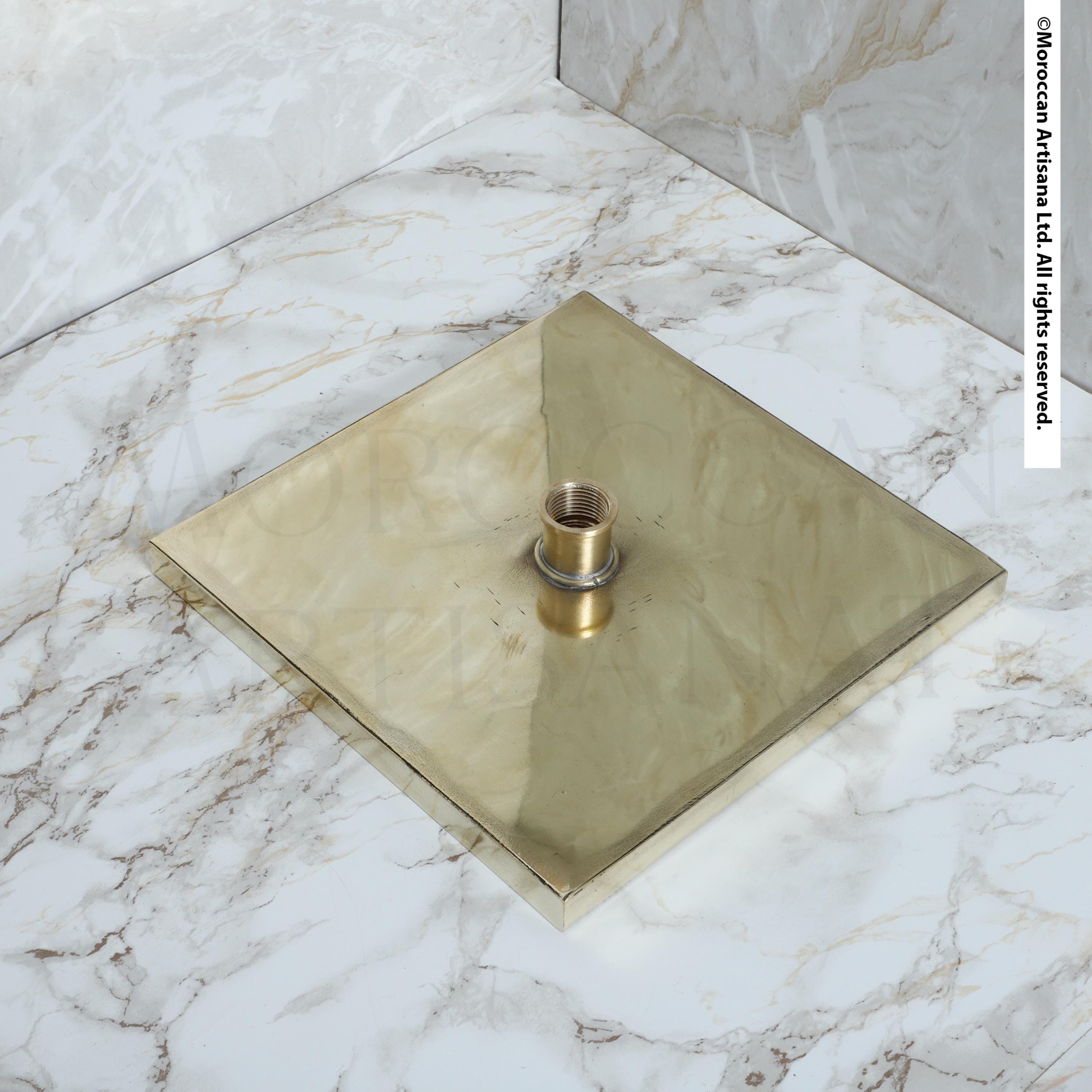 a square brass-colored object placed on a marble countertop.