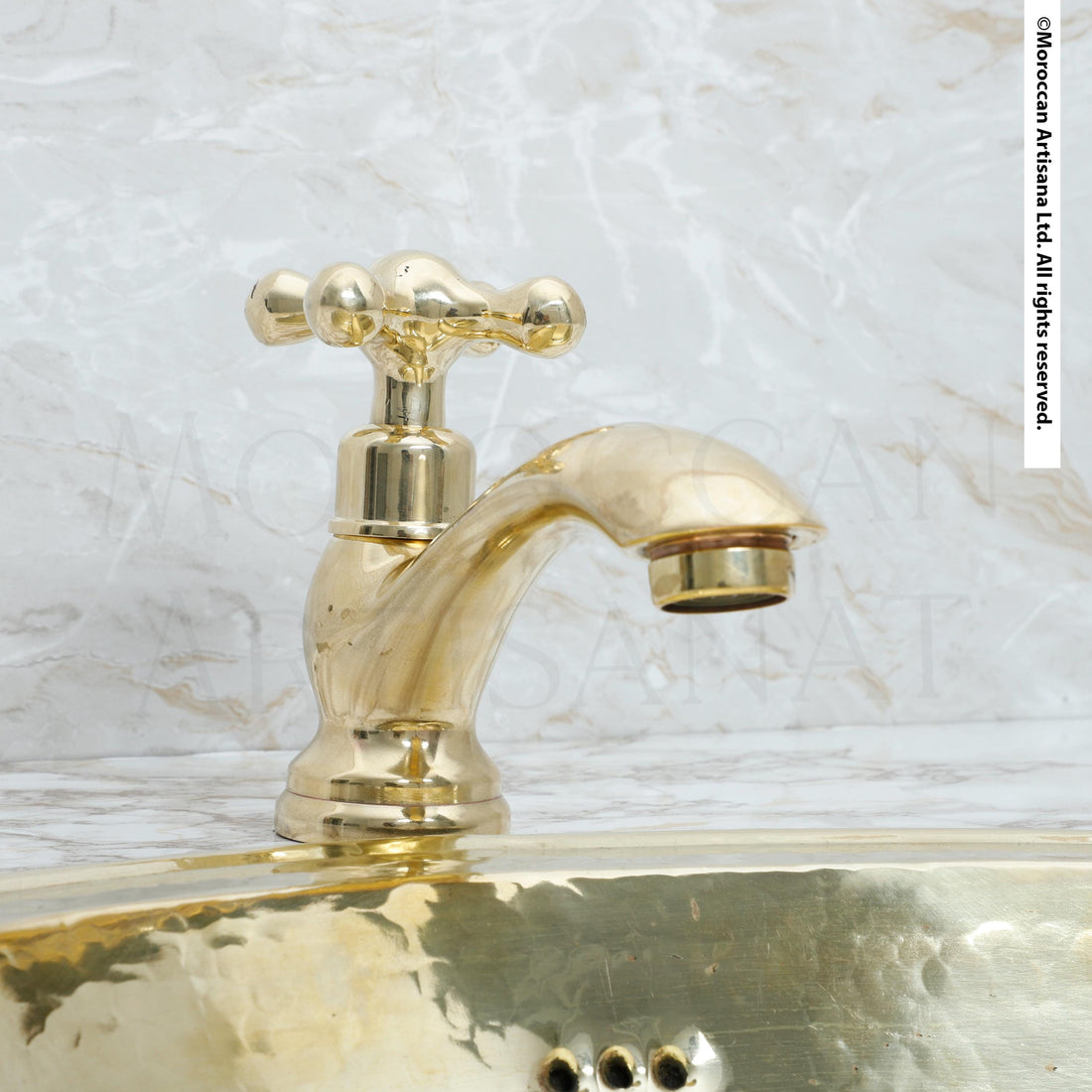 A shiny gold-colored faucet is mounted on a marble countertop.