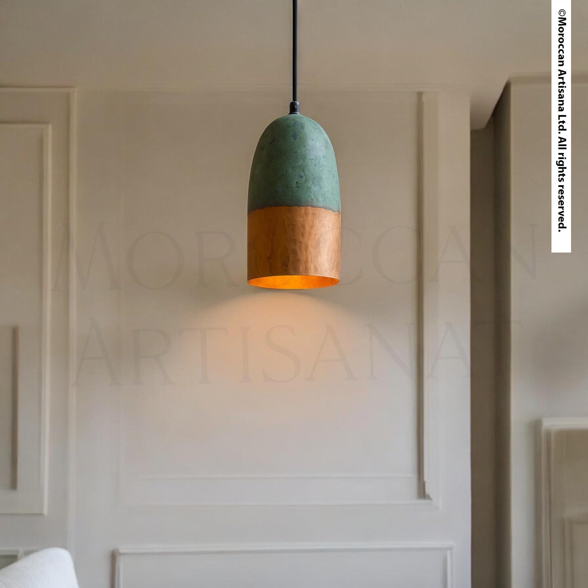 A modern pendant light with a green and orange color scheme hangs from the ceiling in a minimalist room with white walls.