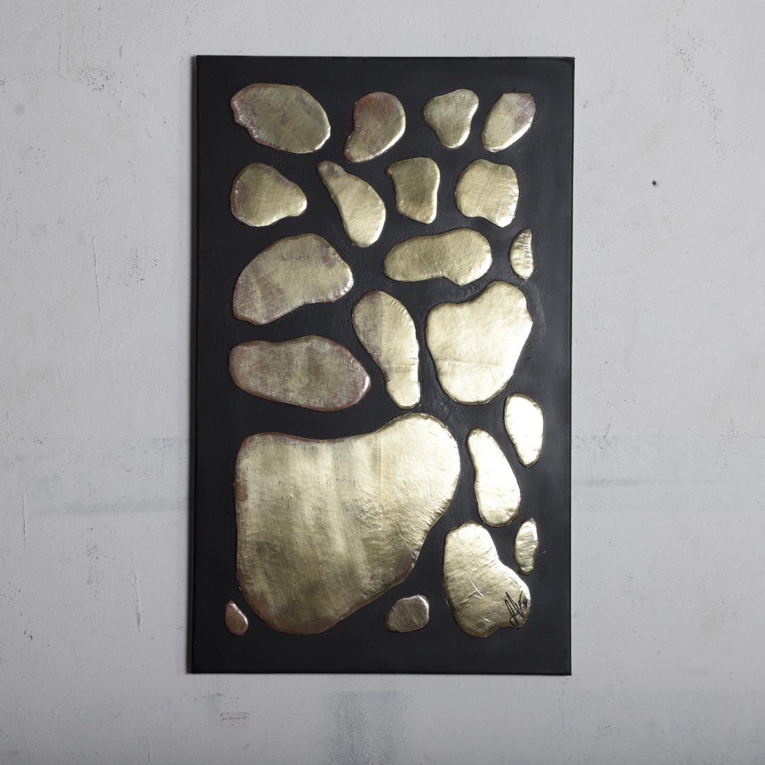 The image is a black rectangular artwork with a gold-colored design on it, featuring a variety of shapes and sizes.