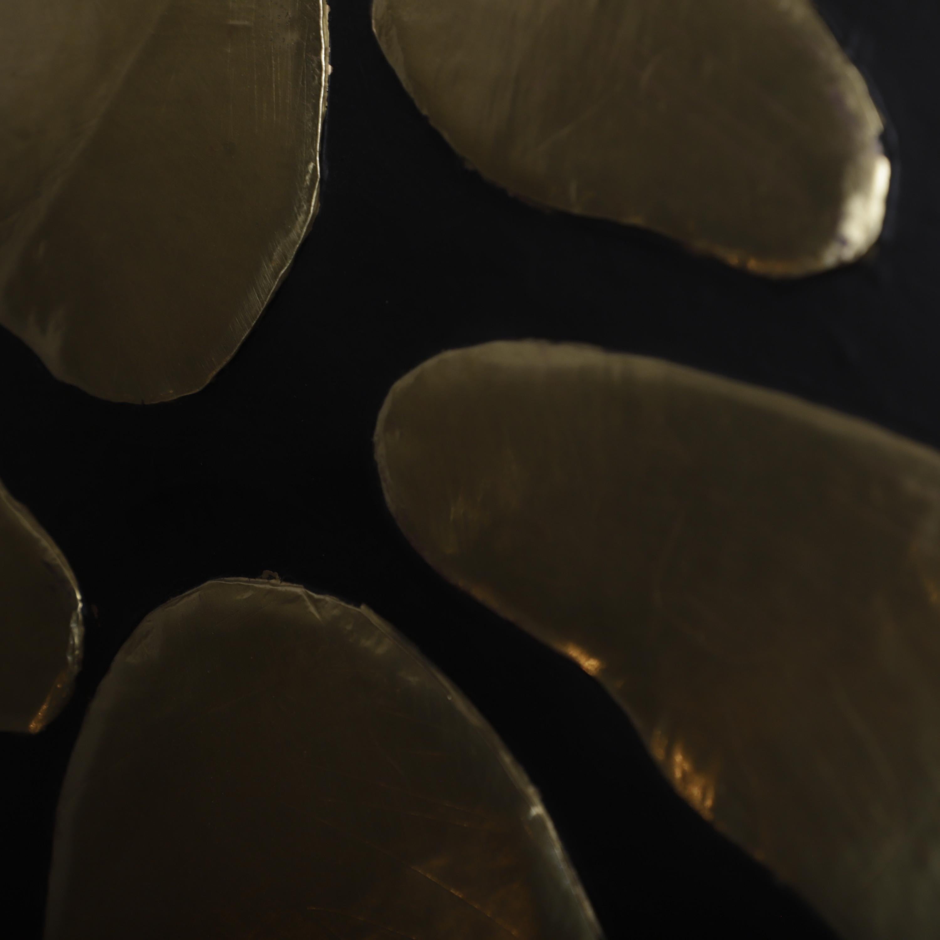 several overlapping, shiny, metallic shapes that appear to be made of a shiny material, possibly gold or silver.