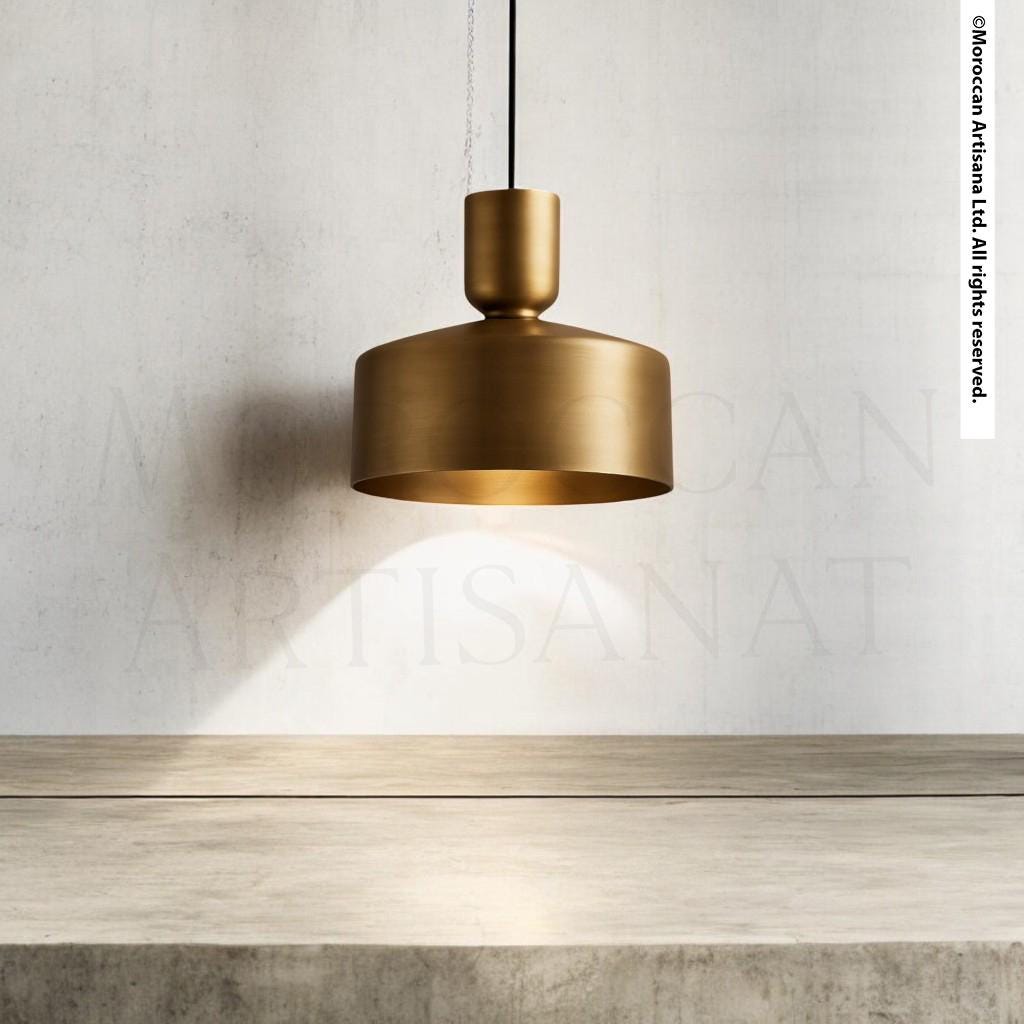 A modern gold pendant lamp hangs from the ceiling, casting a warm glow on the concrete counter below.