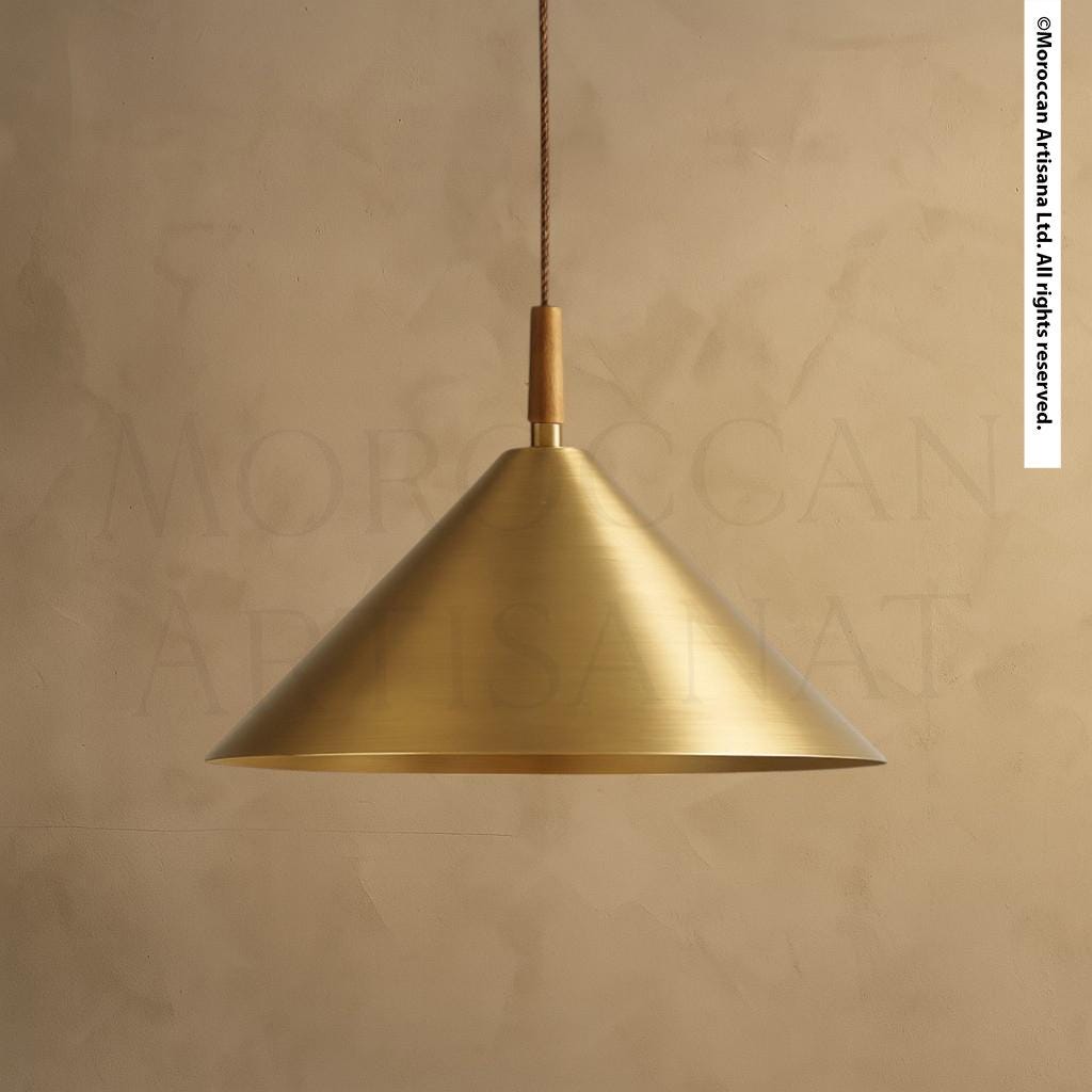 A gold-colored pendant light fixture hangs from a cord against a beige background.