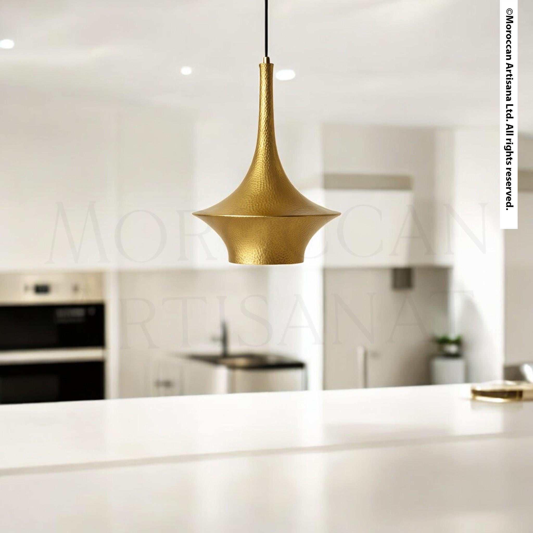 A modern kitchen with a gold pendant light hanging above a white countertop.