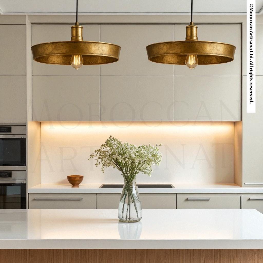 a modern kitchen with a white countertop, a vase of white flowers, and two hanging pendant lights.
