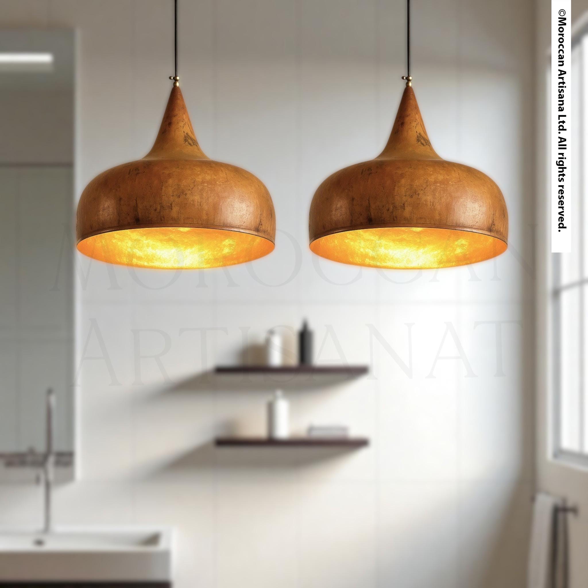 two pendant lights hanging from the ceiling in a modern bathroom, with a shelf below them and a window in the background.