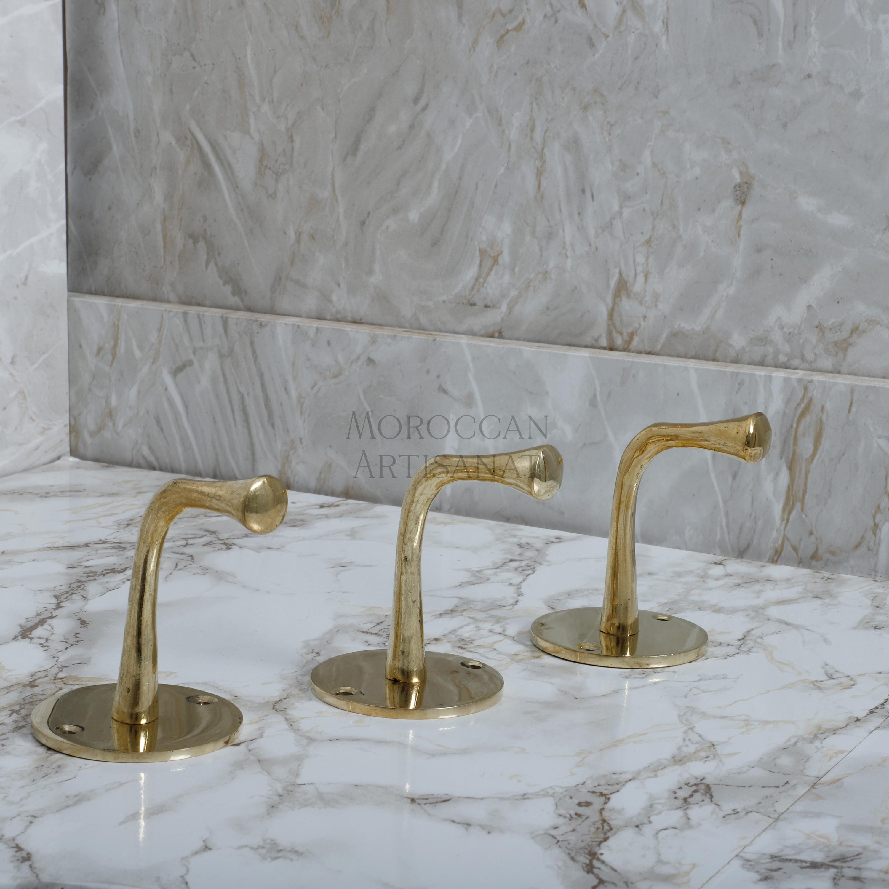 two golden faucets on a marble counter top