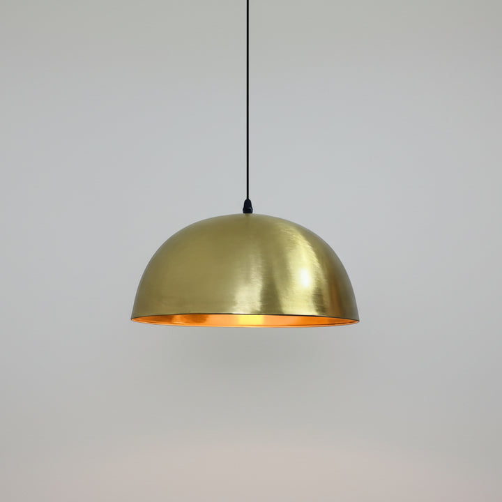 A gold-colored pendant light hangs from the ceiling against a beige wall.