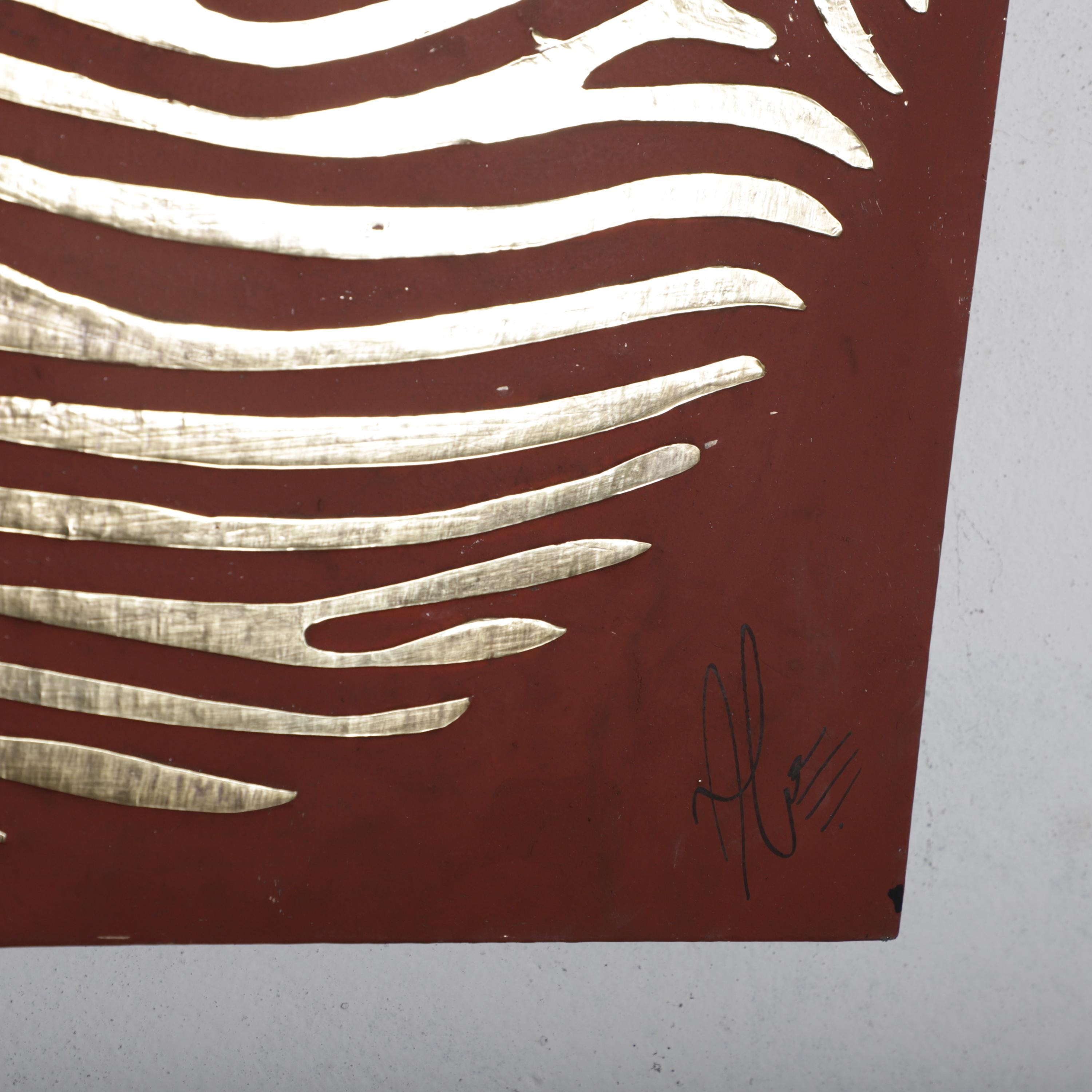 a close-up view of a red surface with a gold-colored design resembling a zebra pattern.