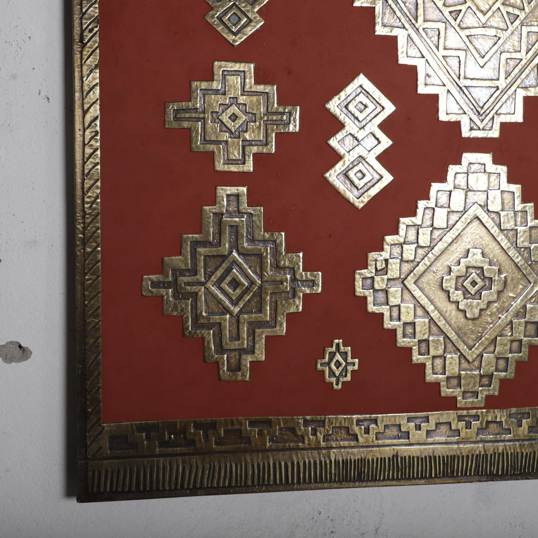 a close-up view of a red surface adorned with intricate geometric patterns and designs, including diamond shapes and other geometric forms.