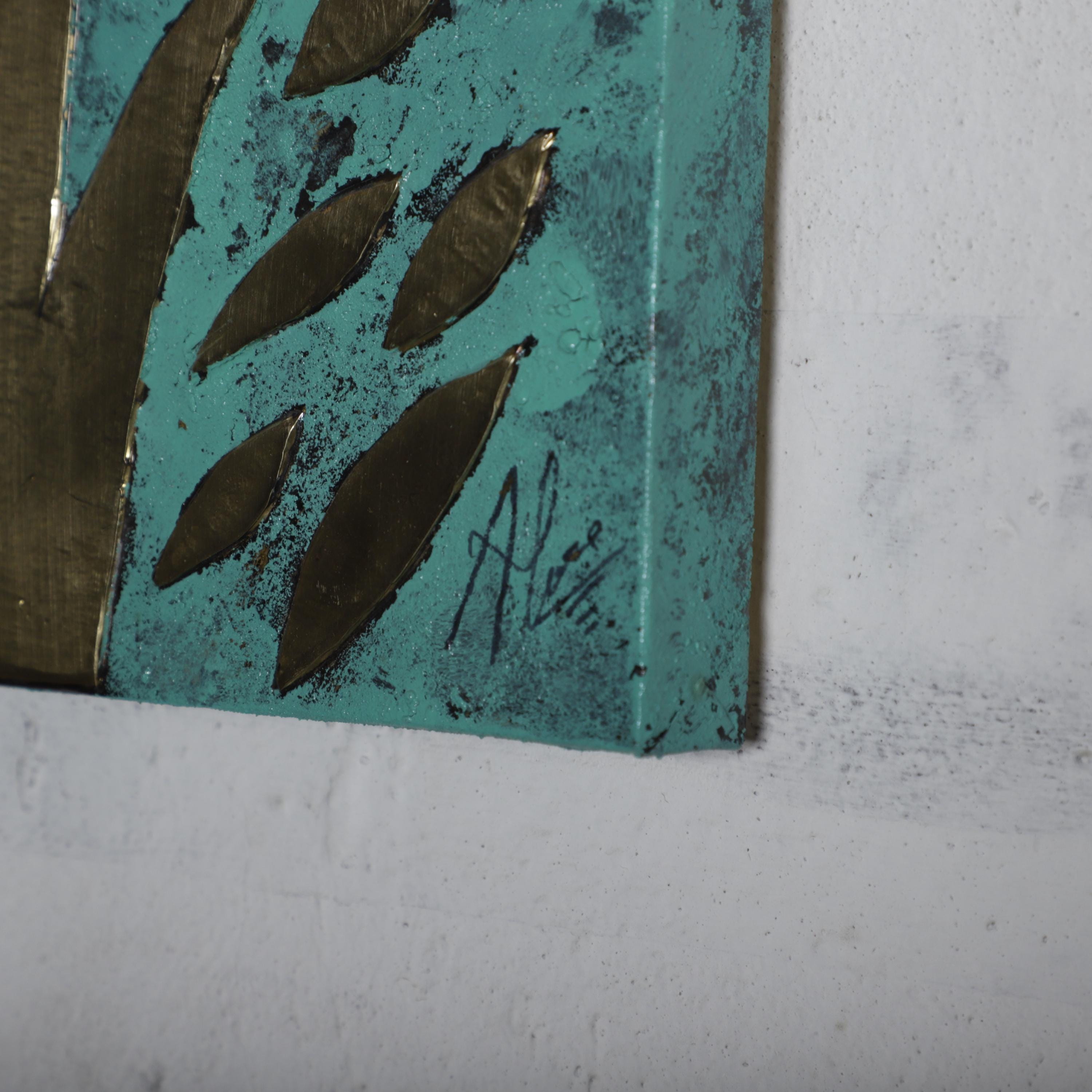 a close-up view of a piece of art with a teal background and metallic leaf-like shapes.