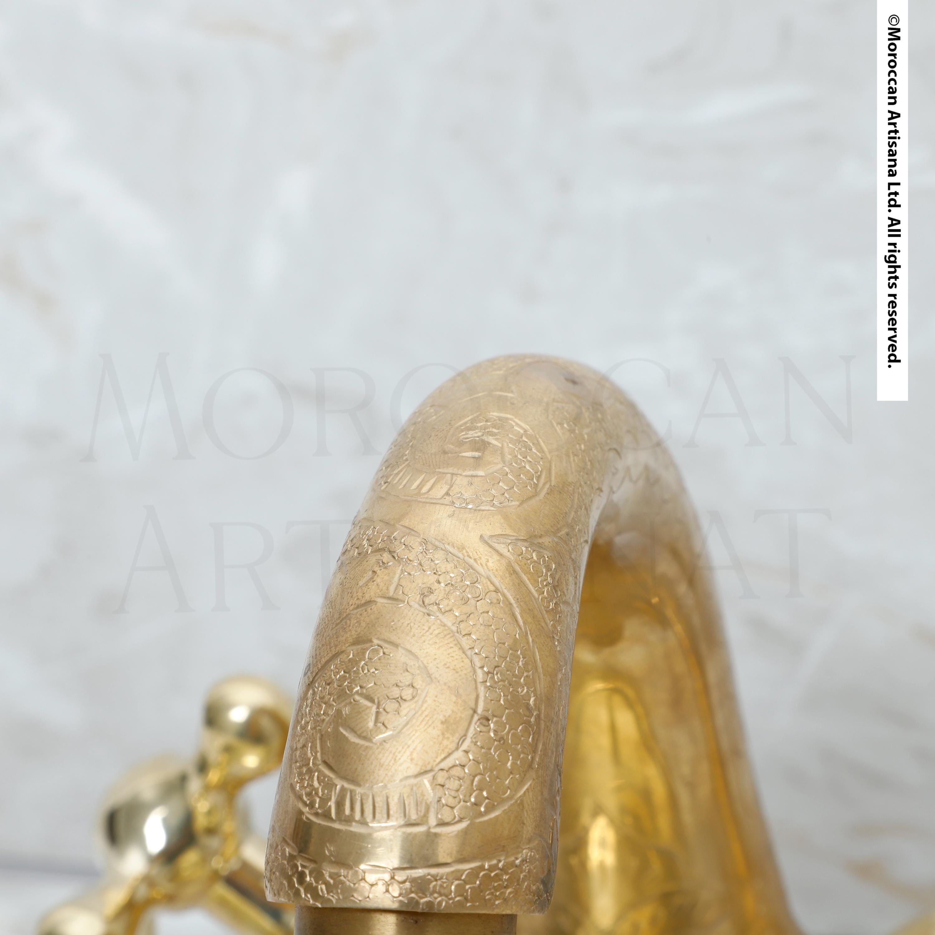 A close-up view of a decorative golden handle or faucet, with intricate patterns and designs visible.