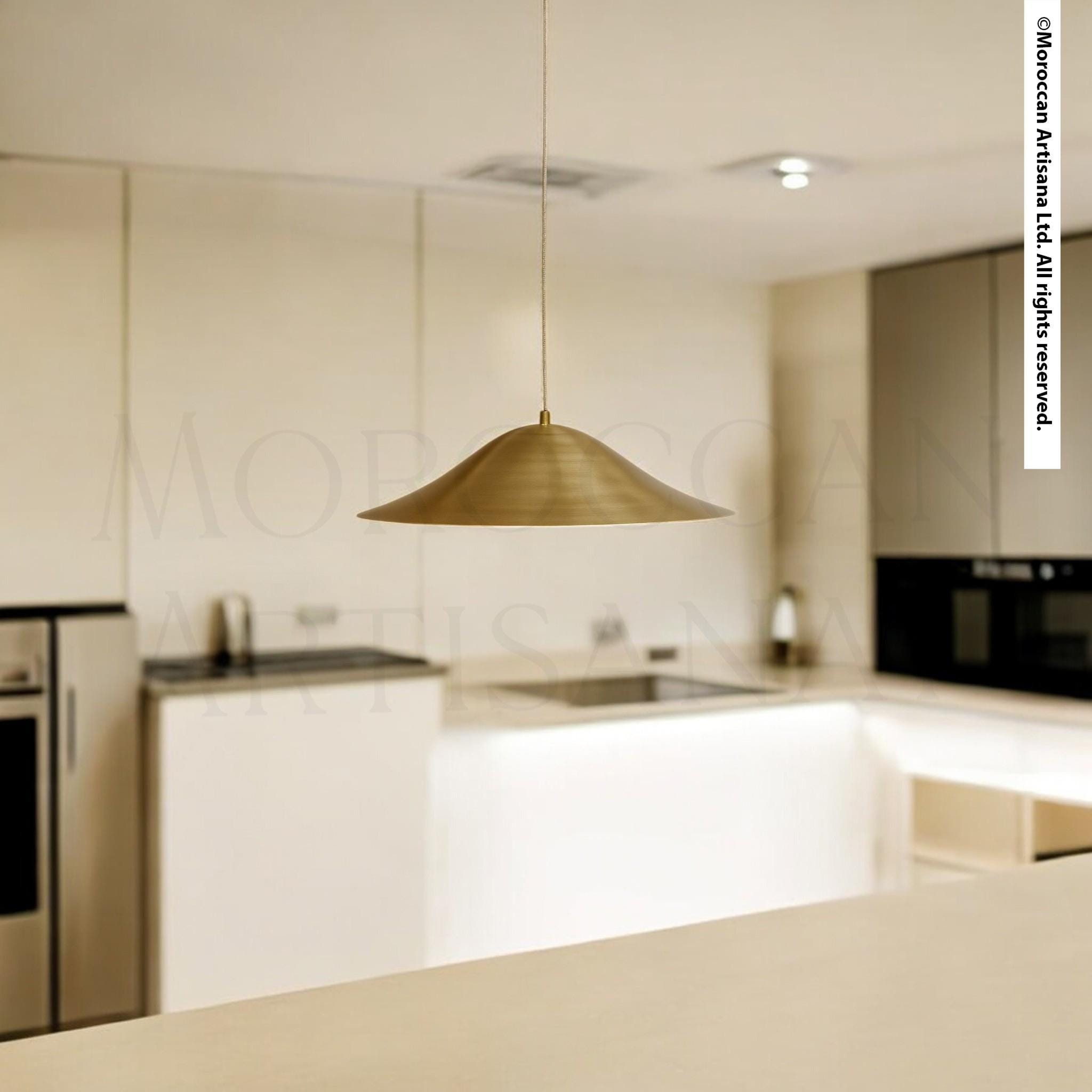 A modern kitchen with a sleek, minimalist design. The focal point is a pendant light hanging from the ceiling, casting a warm glow over the space. The kitchen features white cabinets, a black countertop, and stainless steel appliances, creating a clean and contemporary look.