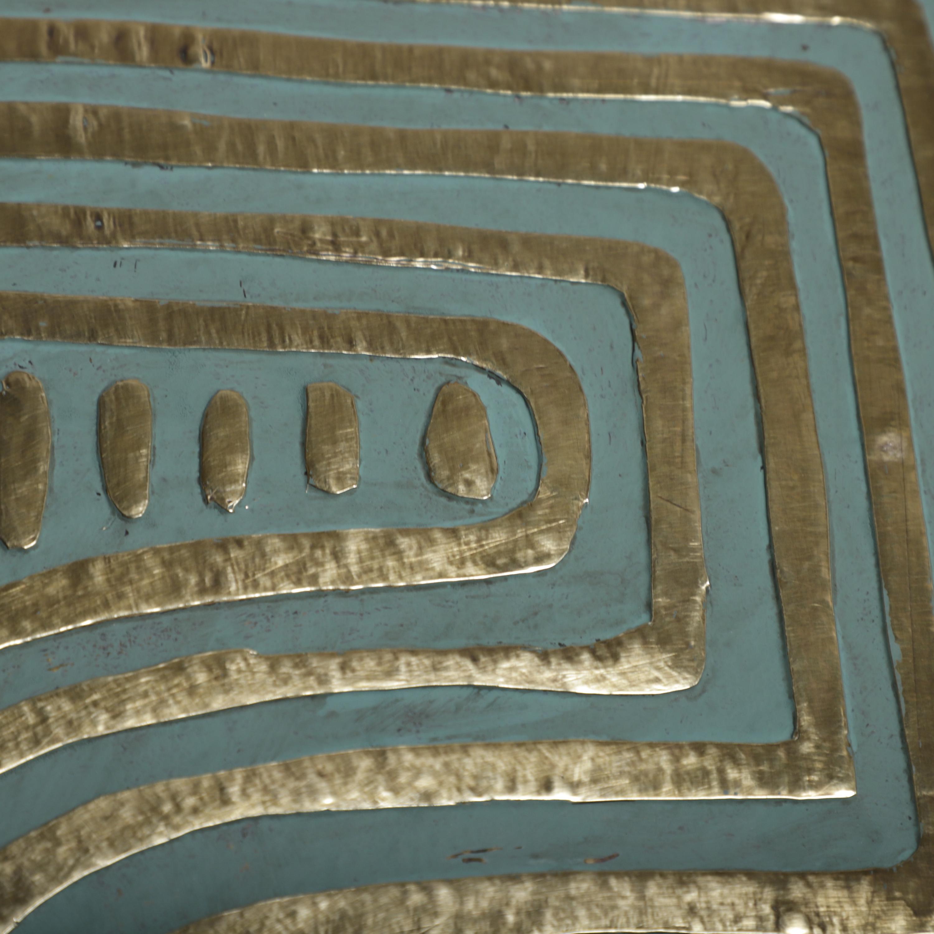 a close-up view of a metallic surface with a repeating pattern of curved lines in shades of blue and gold.