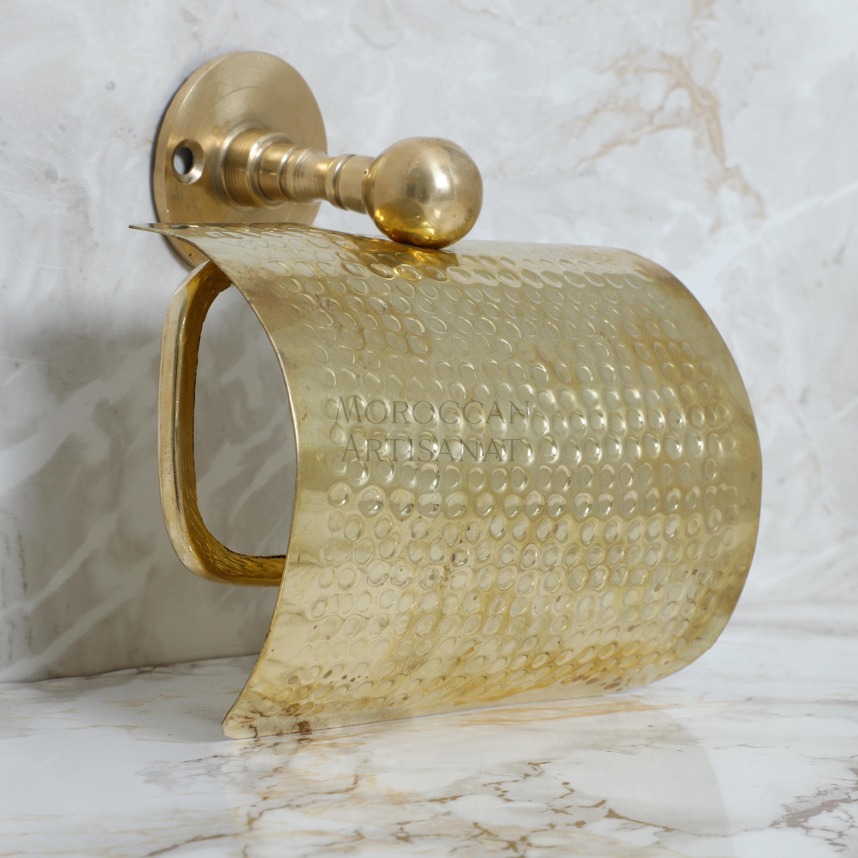 a gold toilet paper holder on a marble wall
