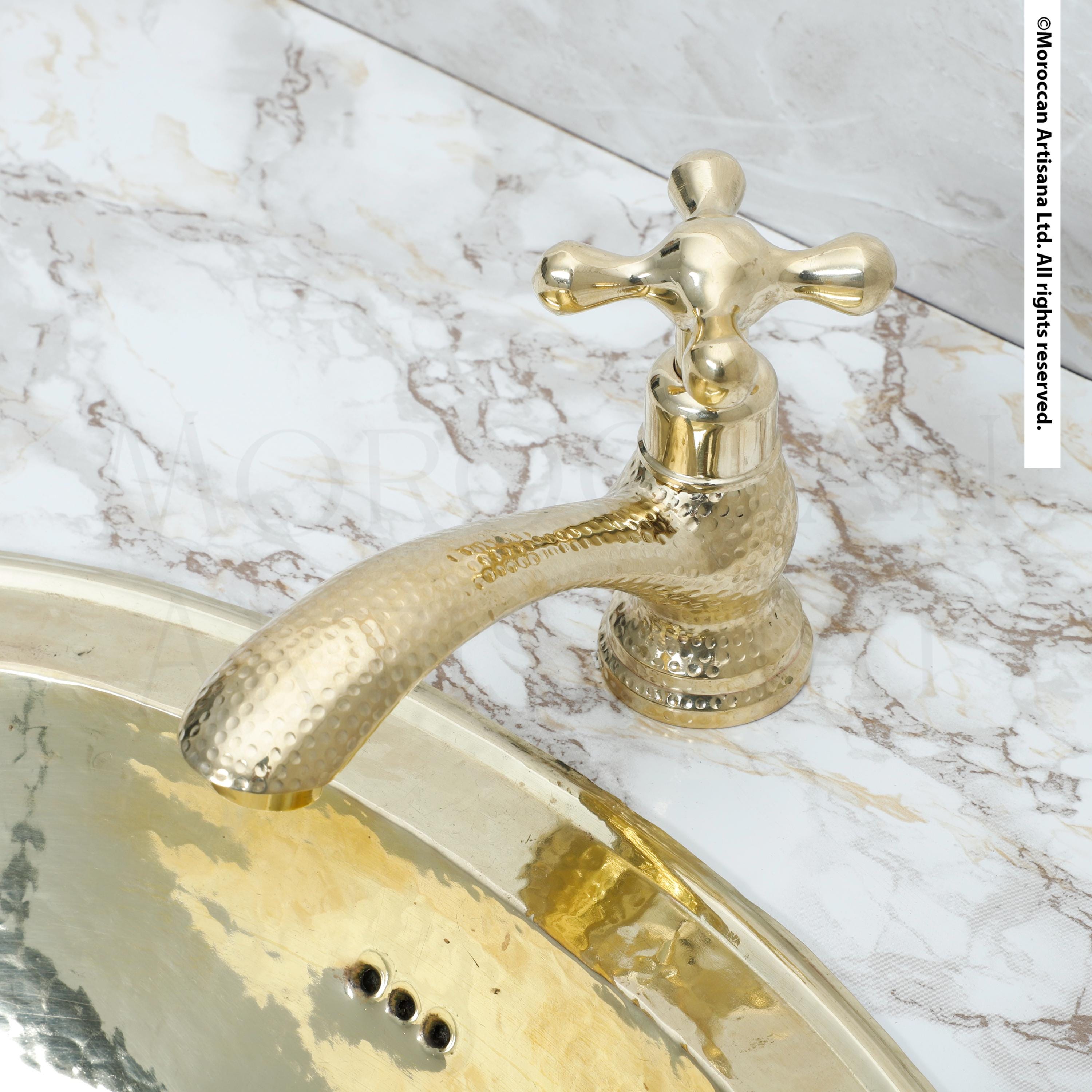 A close-up view of a gold-colored bathroom faucet and sink set against a marble countertop.