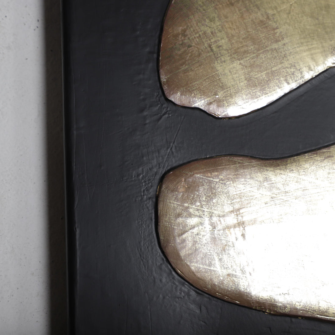 a close-up view of a black surface with two overlapping metallic shapes, one appearing to be a piece of metal or a metallic object.