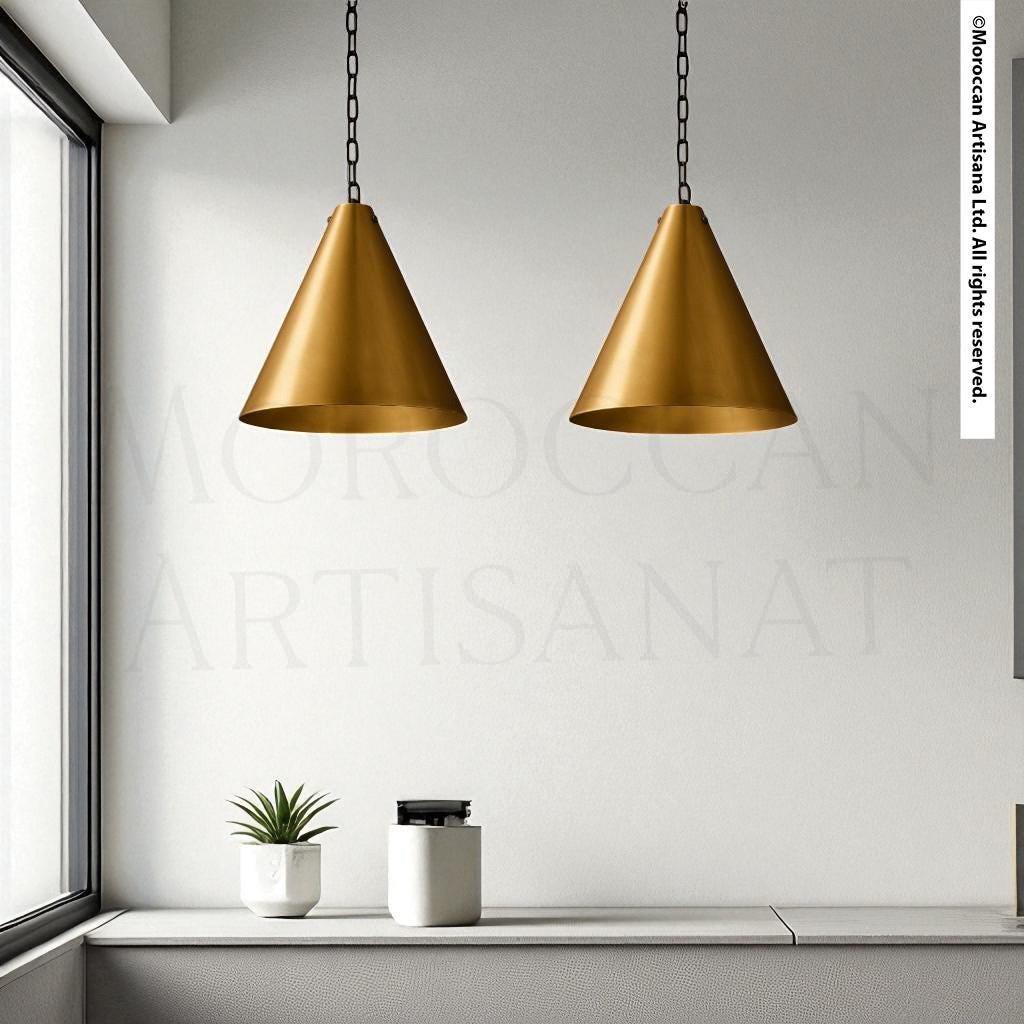 a minimalist interior design with two gold-colored pendant lights hanging from the ceiling, a small potted plant on a shelf, and a white vase on a table.