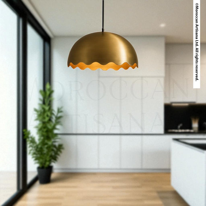 a modern kitchen with a large potted plant and a hanging gold-colored pendant light.
