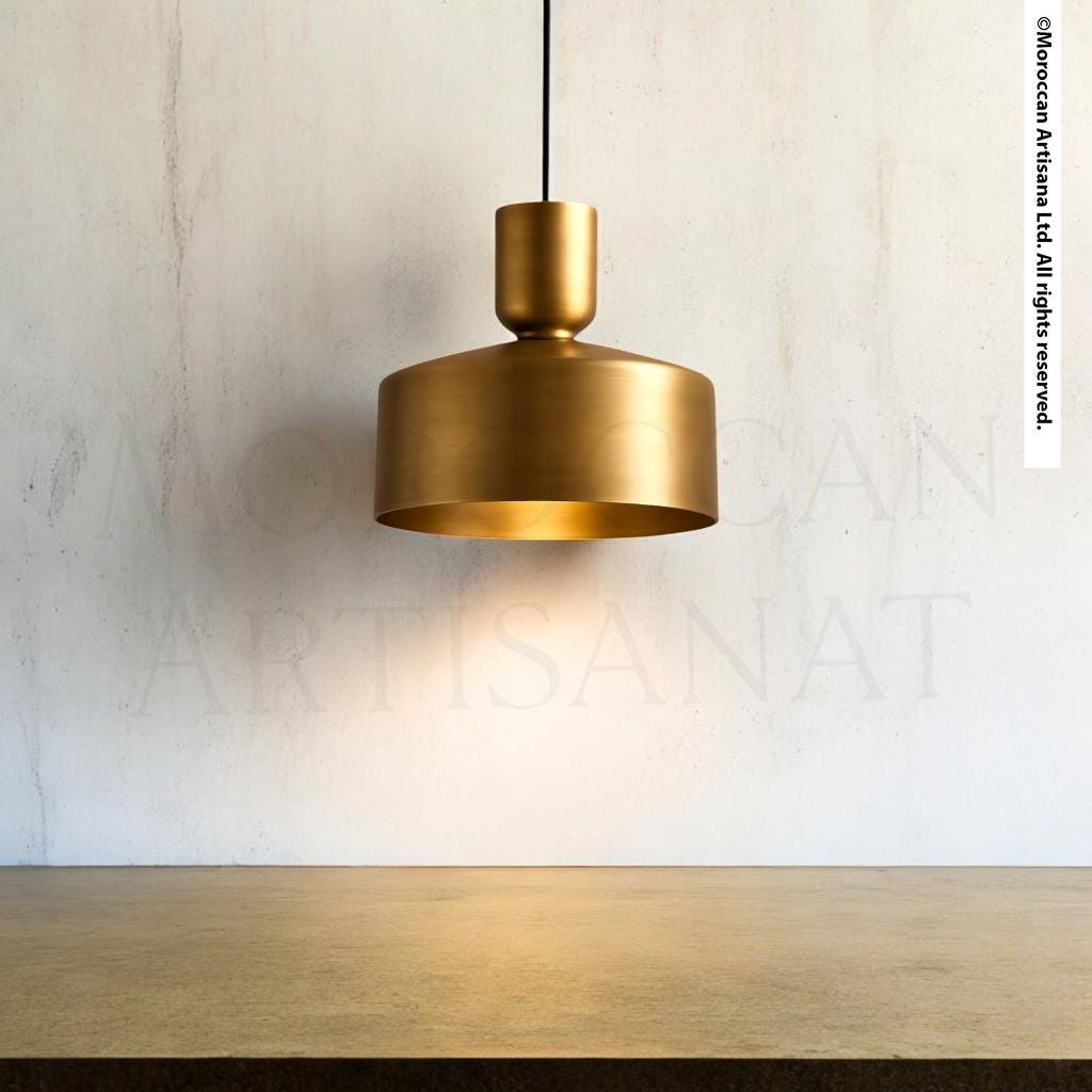 A gold-colored pendant light hangs from the ceiling, casting a warm glow on the wooden table below.