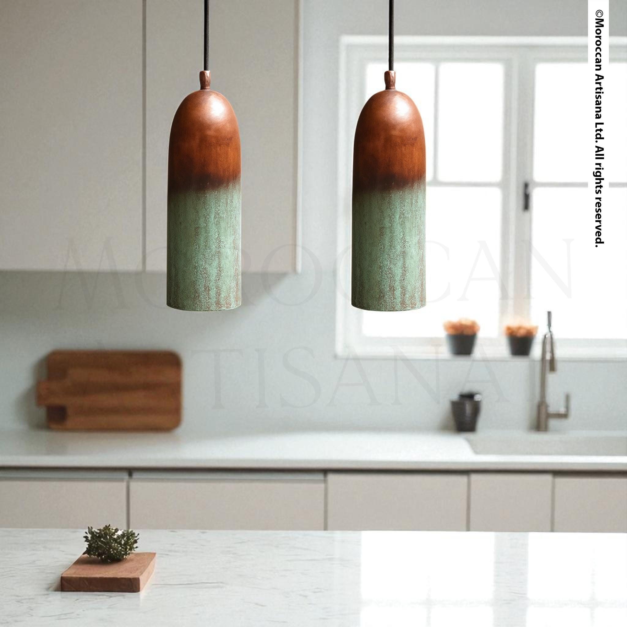 a modern kitchen with two pendant lights hanging above a wooden cutting board. The kitchen has white cabinets and a marble countertop, creating a clean and minimalist aesthetic.