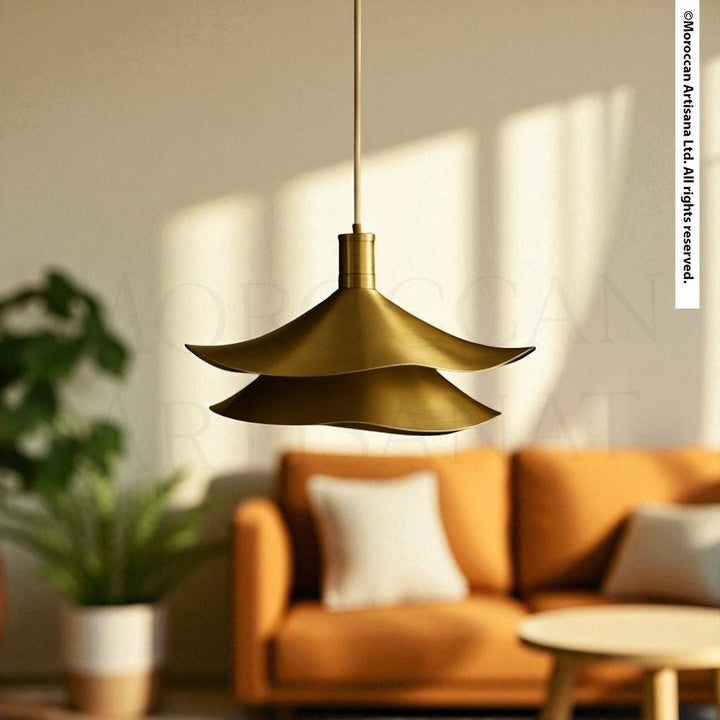 a modern, gold-colored pendant light hanging from the ceiling, illuminating a cozy living room with a plush orange sofa and a wooden coffee table.