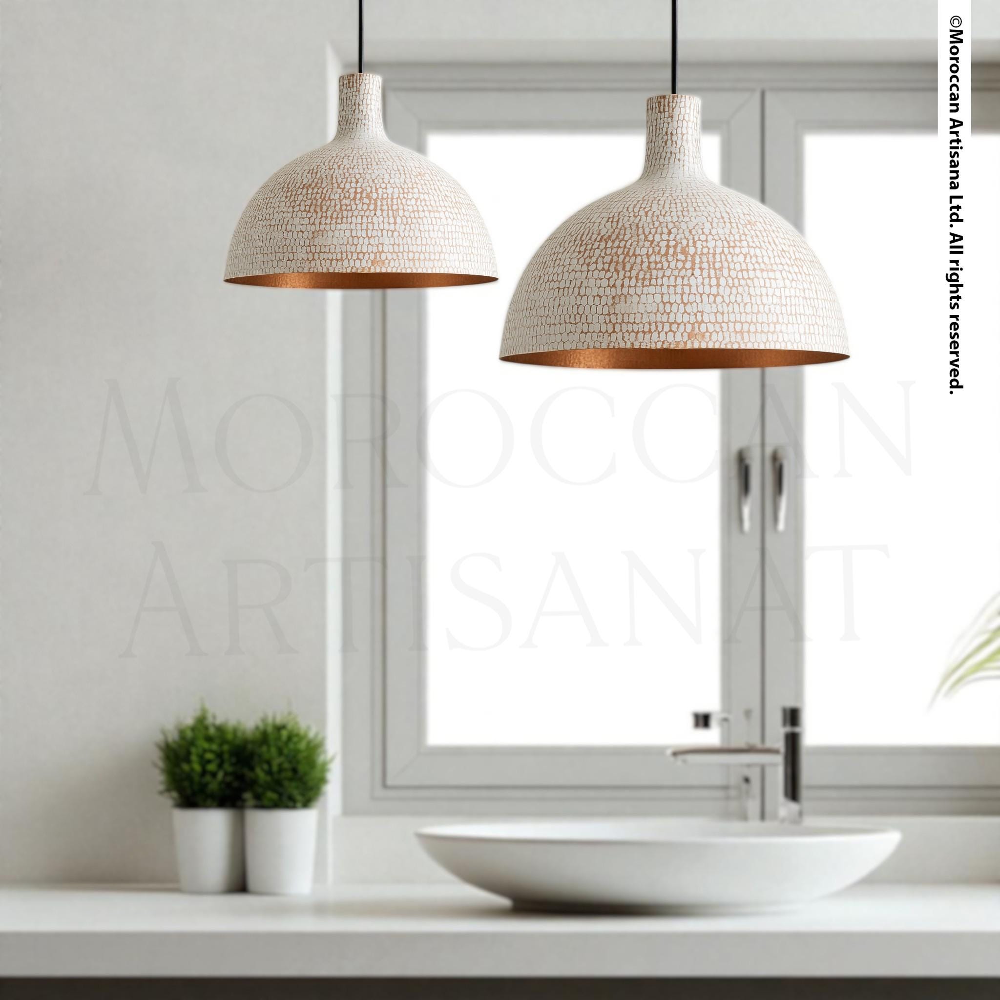 a modern bathroom with a white sink, two pendant lights, and a plant on the windowsill.