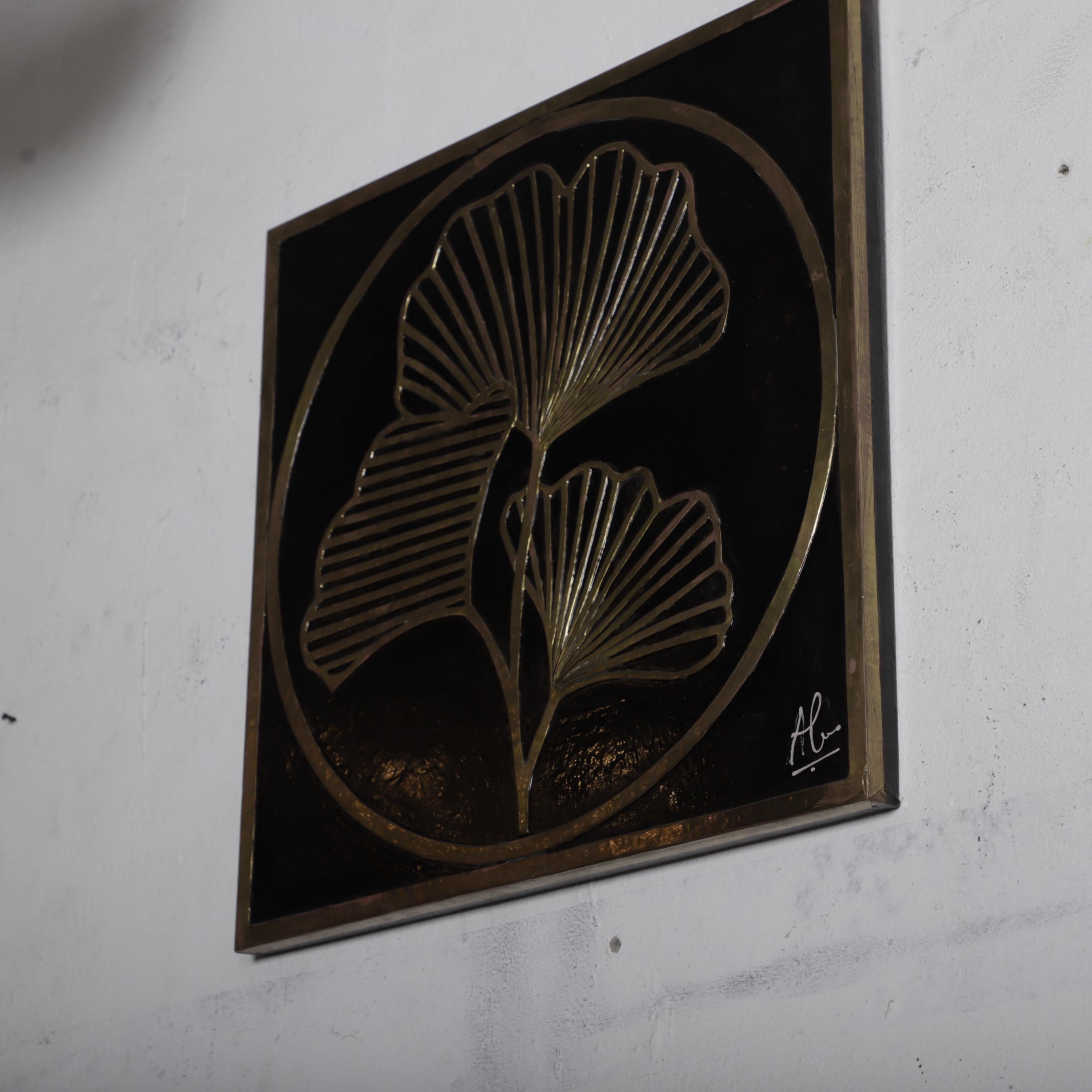 a decorative metal plaque with a stylized design of two leaf-like shapes on a black background.