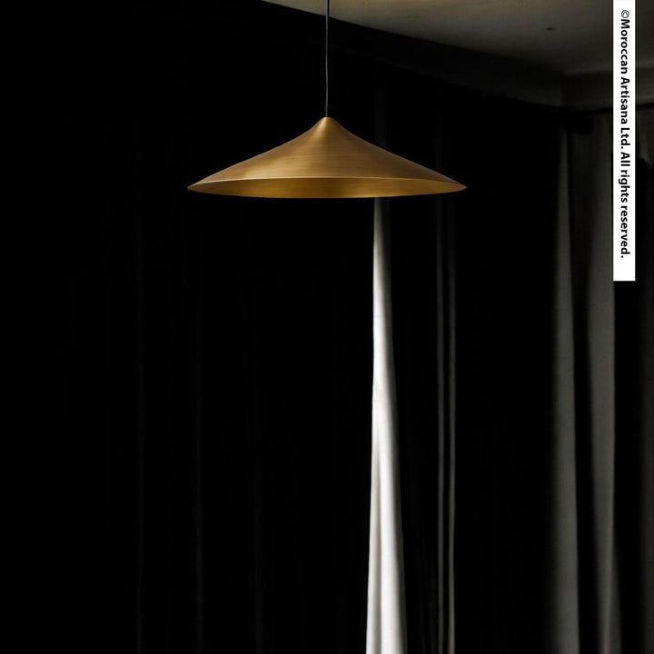 A gold pendant lamp hangs from the ceiling, casting a warm glow against a dark background.