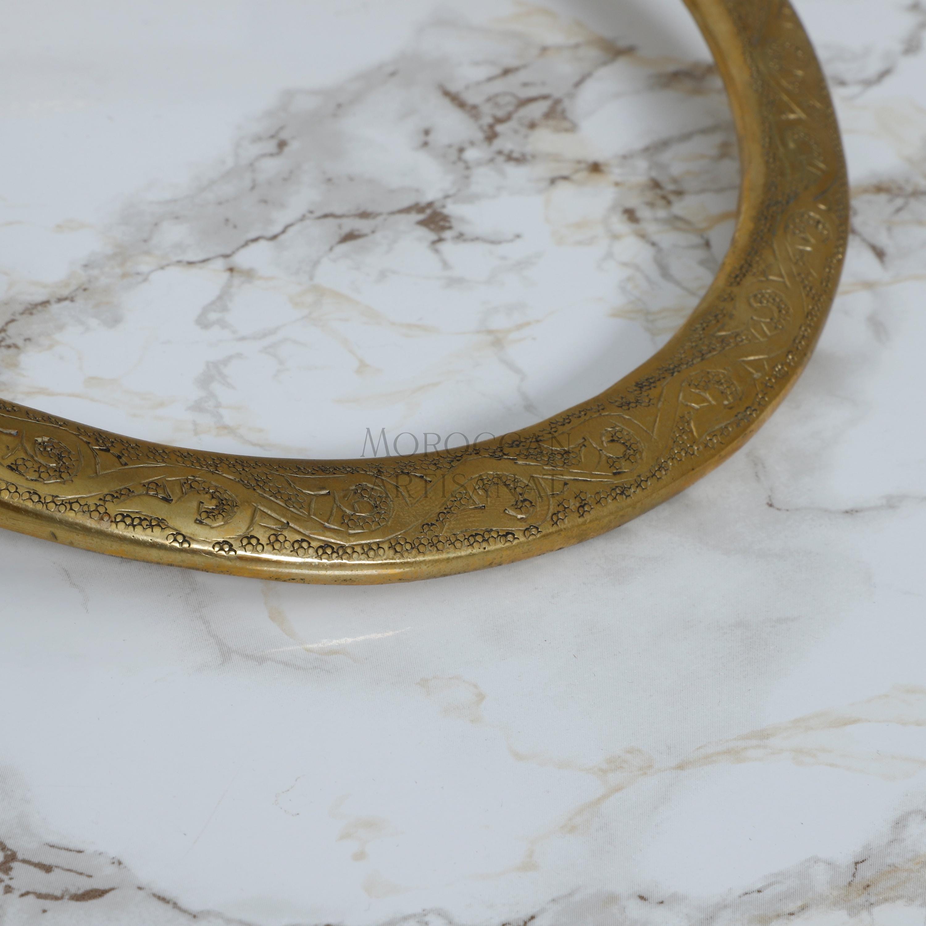 a close up of a gold bracelet on a marble surface