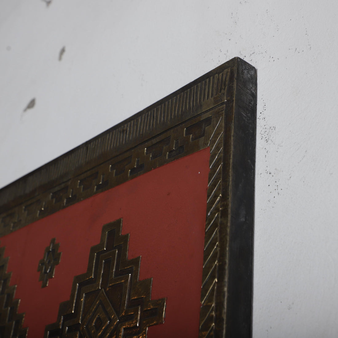 a close-up view of a red and gold decorative frame with a geometric pattern on the surface.