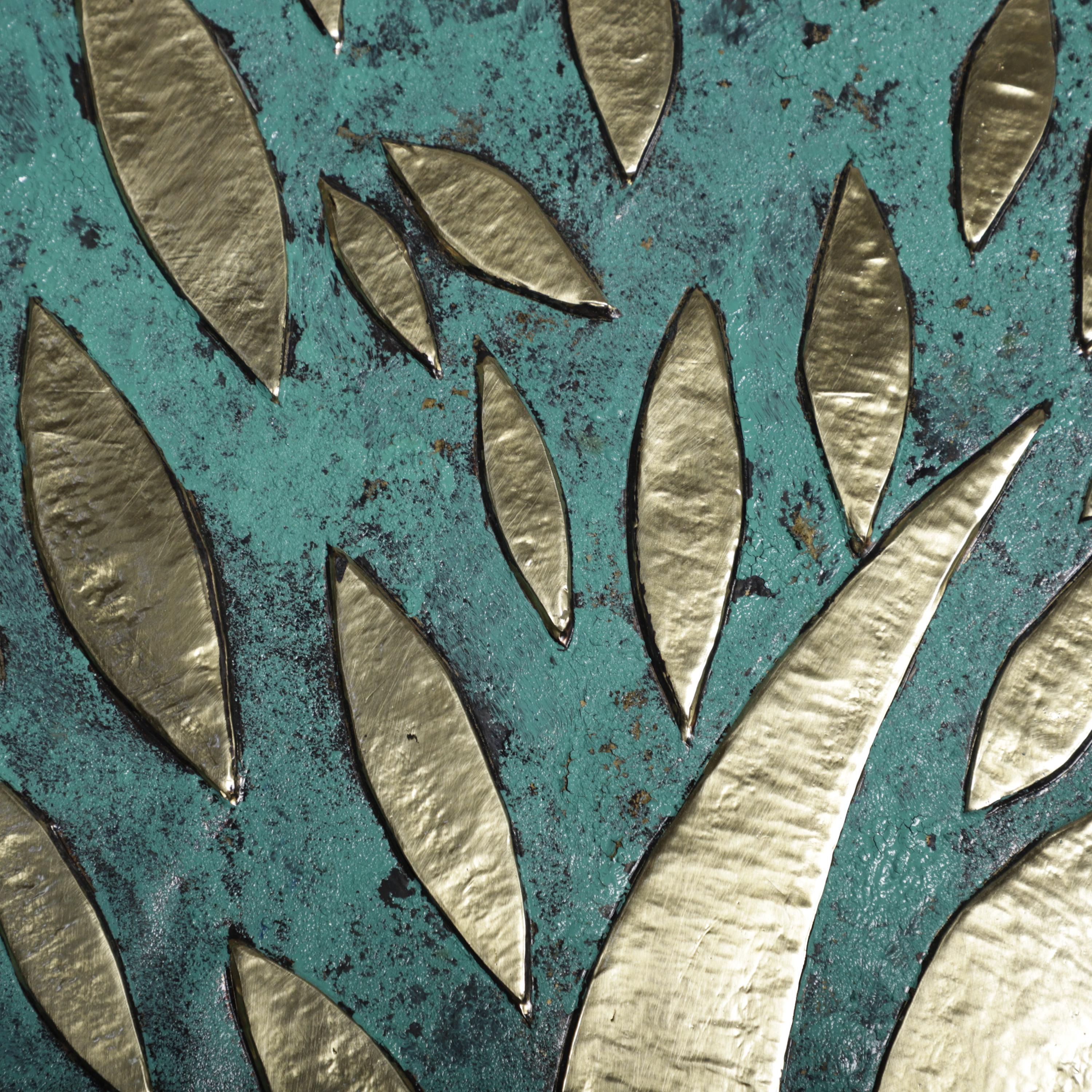 a close-up view of a textured surface with a pattern of metallic leaves or branches. The leaves appear to be made of a shiny material, possibly gold or silver, and are arranged in a repeating pattern across the surface. The background is a dark blue-green color, providing a contrast to the metallic leaves.
