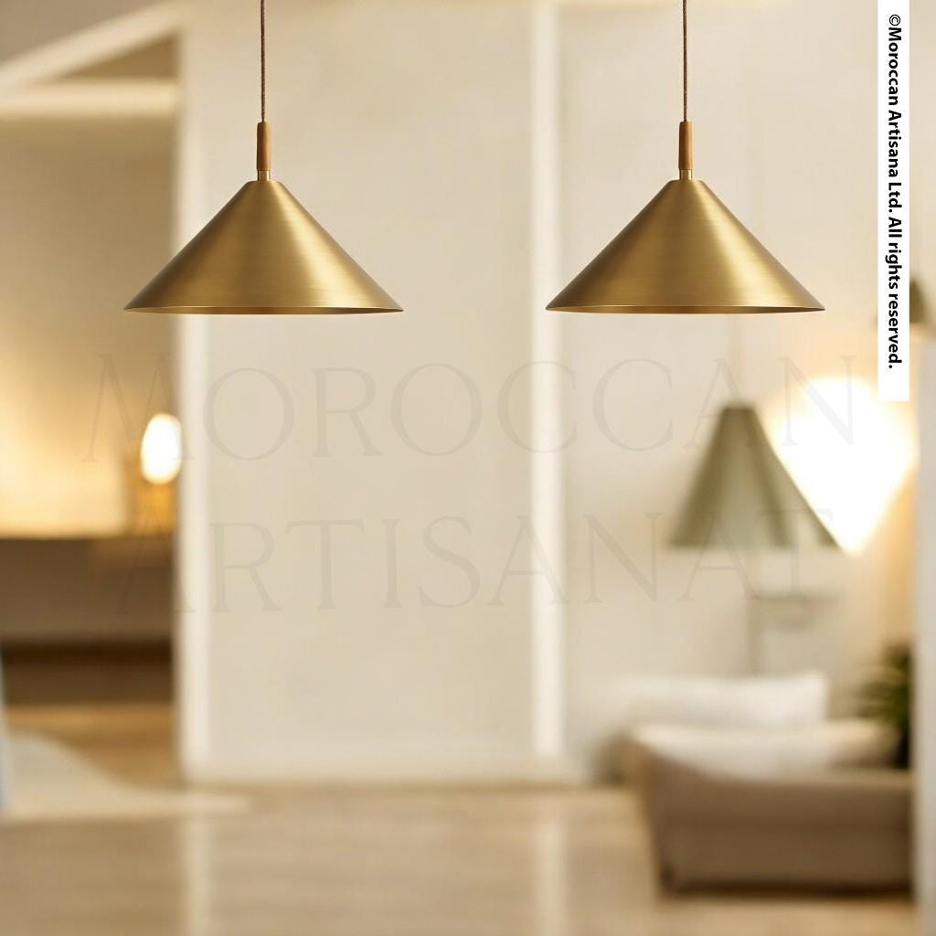 two gold-colored pendant lights hanging from the ceiling in a modern, minimalist living room setting.