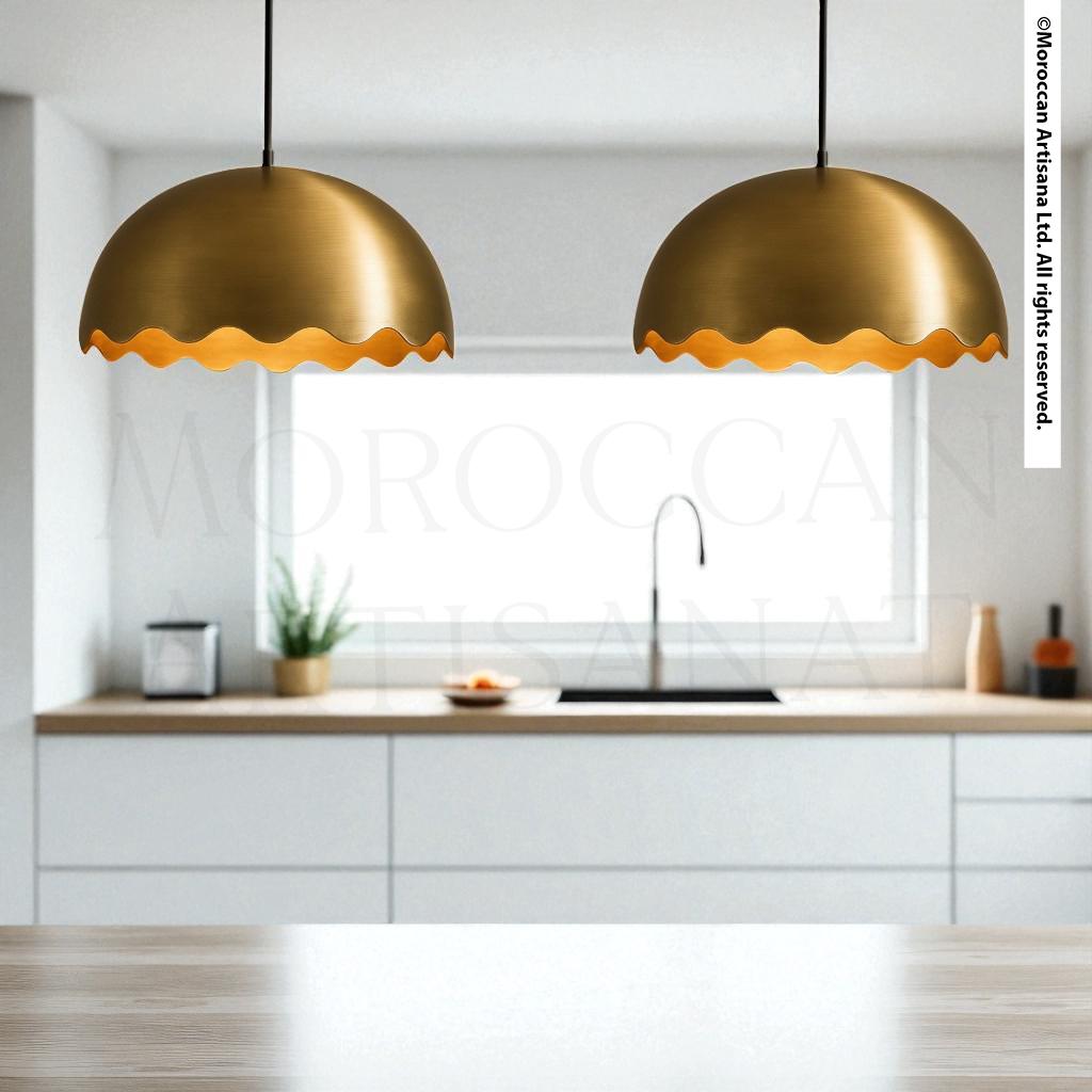 a modern kitchen with a pair of gold-colored pendant lights hanging above a wooden countertop.